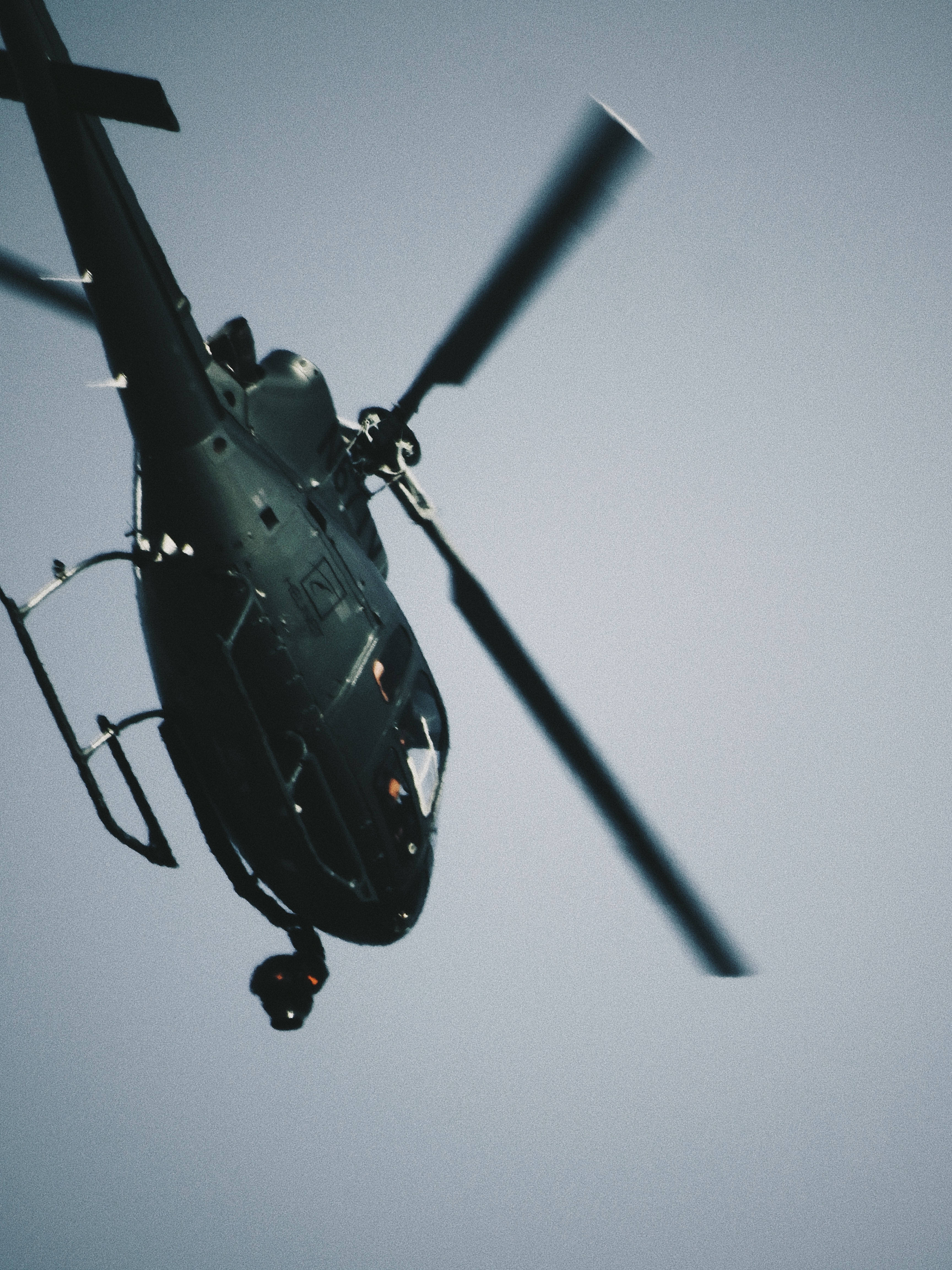 Helicopter 桌布 壁紙 — 一架深色直升機在蒼白的天空中盤旋，旋轉的槳葉產生動態模糊。