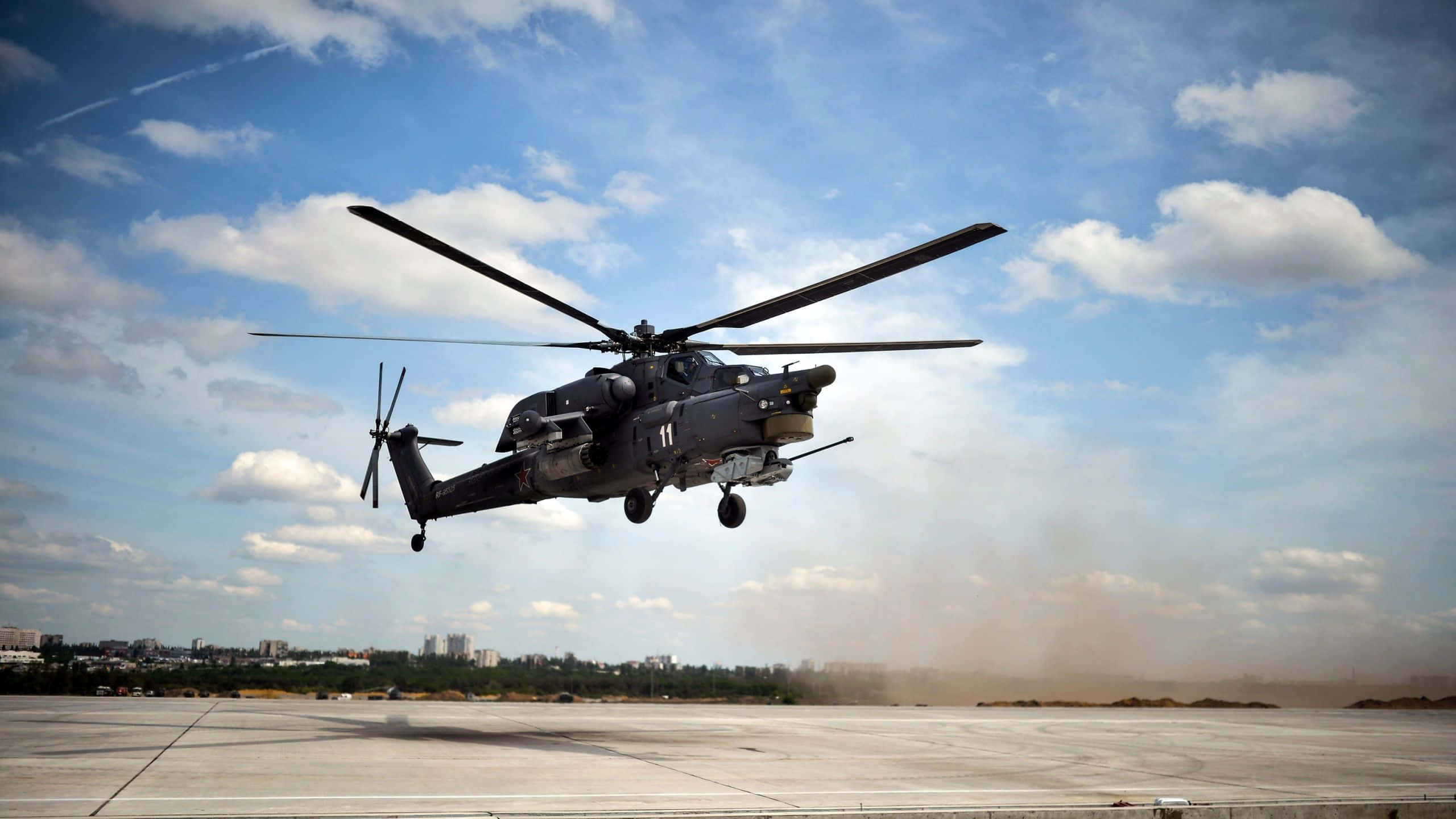 Helicopter 桌布 壁紙 — 一架深色軍用直升機在晴朗藍天和零星雲朵下，從塵土飛揚的機場起飛。