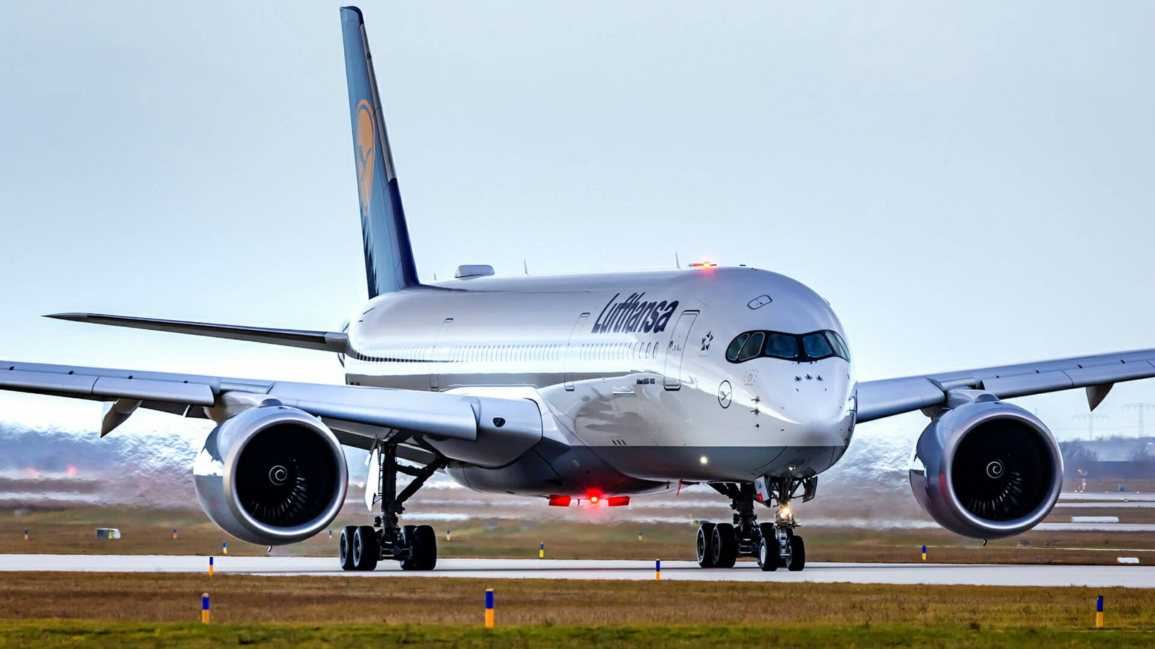 Plane 桌布 壁紙 — 一架漢莎航空空中巴士A350在淡色天空下，於跑道滑行，背景是白雪覆蓋的山脈。