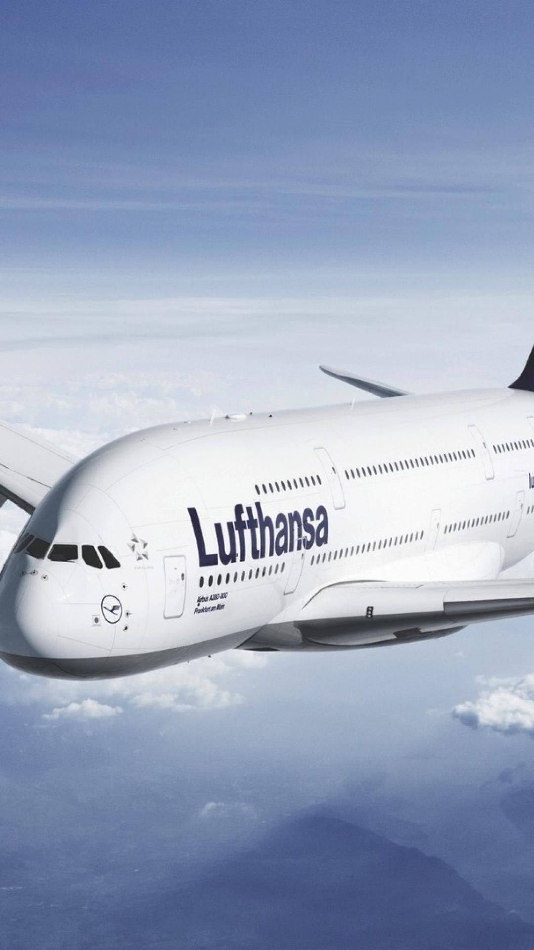 雲朵 桌布 壁紙 — 一架漢莎航空空中巴士A380在晴朗藍天下翱翔於蓬鬆白雲之上，下方有遠山。