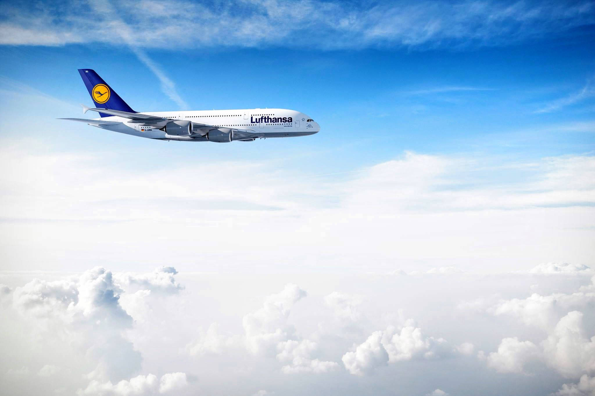 飛機 桌布 壁紙 — 一架漢莎航空空中巴士A380在蔚藍天空和纖細卷雲下，優雅地翱翔於蓬鬆白雲之上。