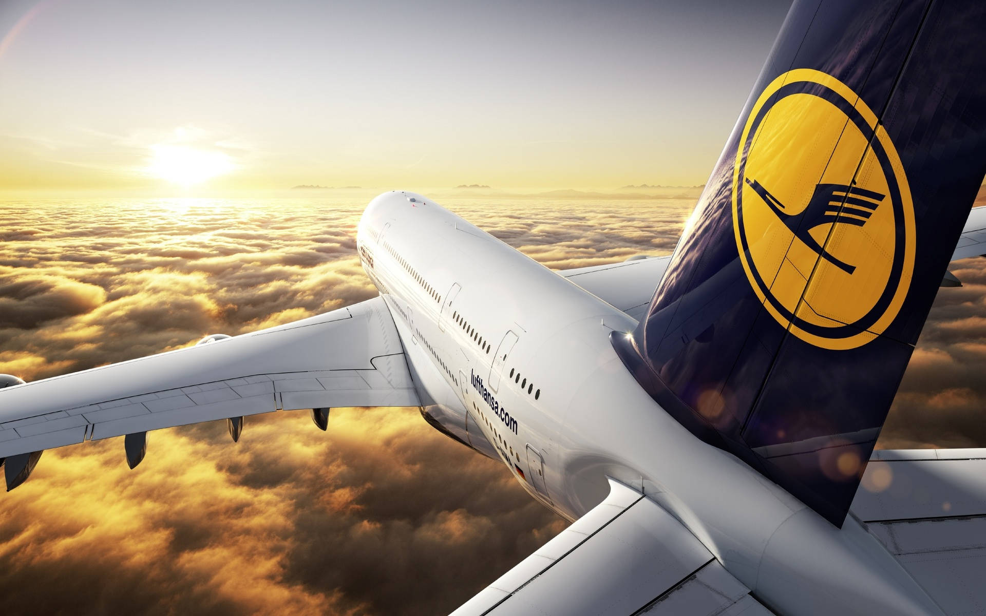 飛機 桌布 壁紙 — 一架漢莎航空飛機在日出時翱翔於金色雲層之上，太陽在地平線上閃耀。