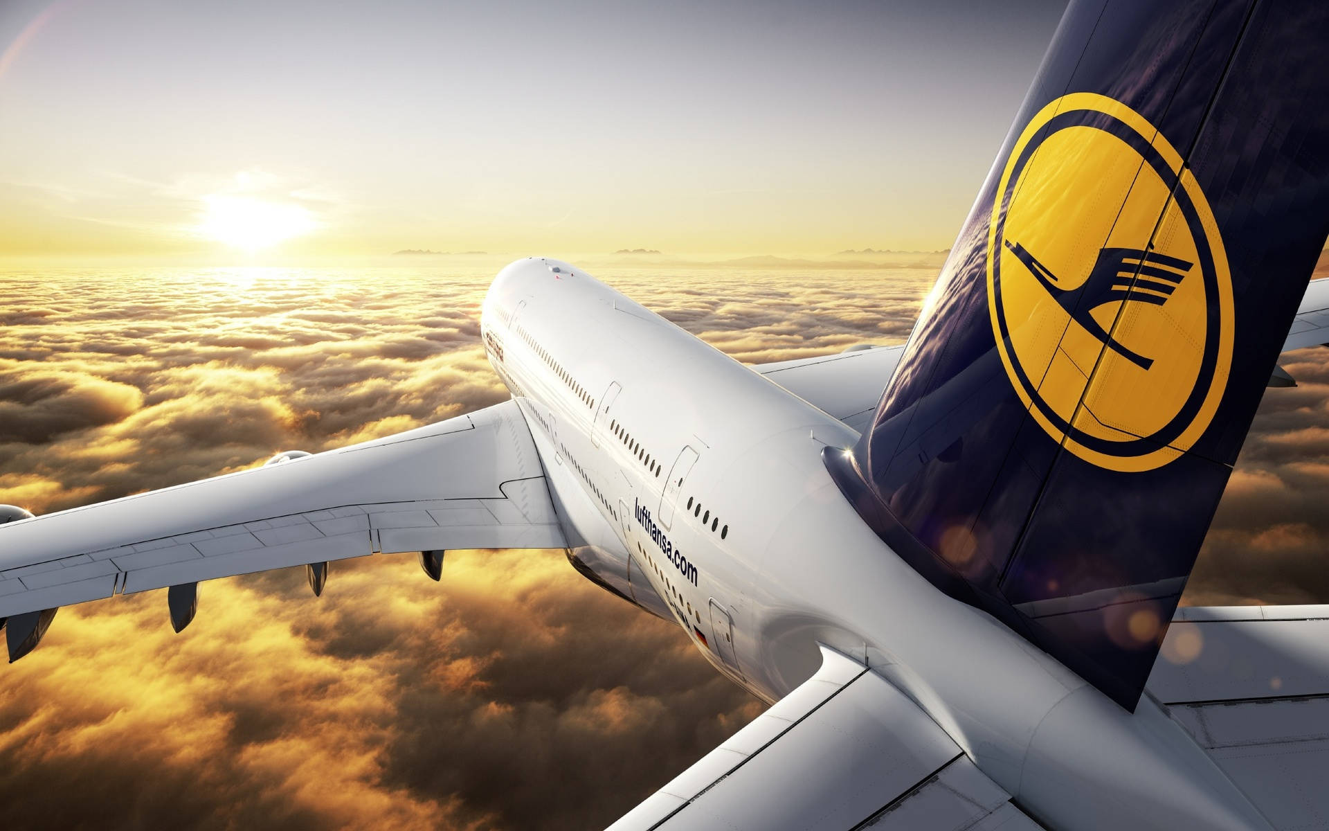 日落 桌布 壁紙 — 一架漢莎航空飛機在日出時翱翔於金色雲層之上，太陽在地平線上閃耀。