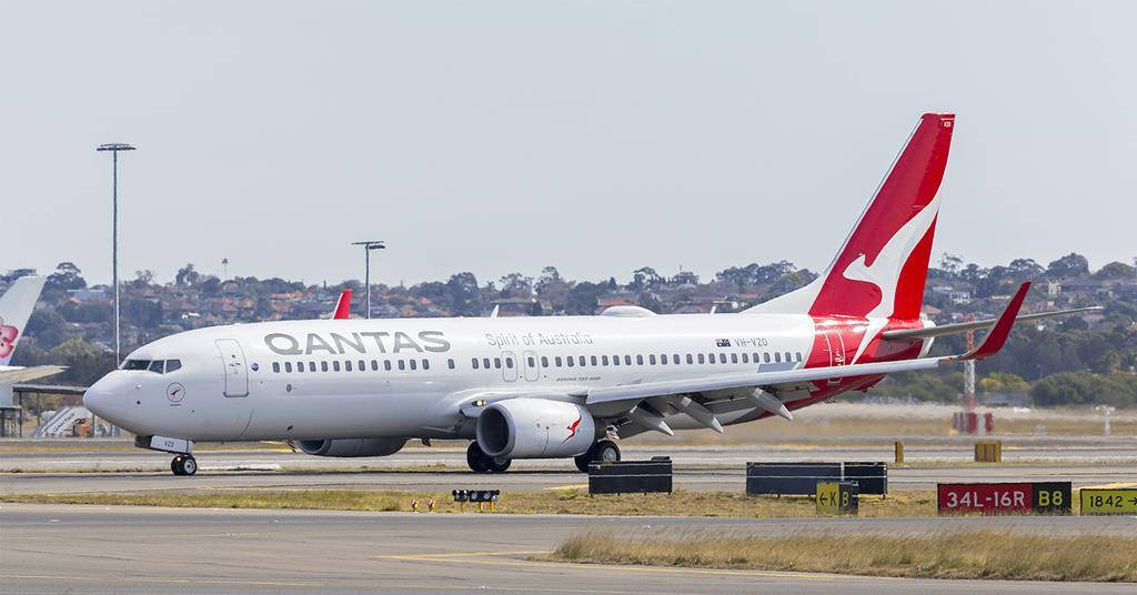 飛機 桌布 壁紙 — 一架澳洲航空Qantas Spirit of Australia的波音737在陽光明媚的機場停機坪上滑行，遠處有樹木和跑道標誌。