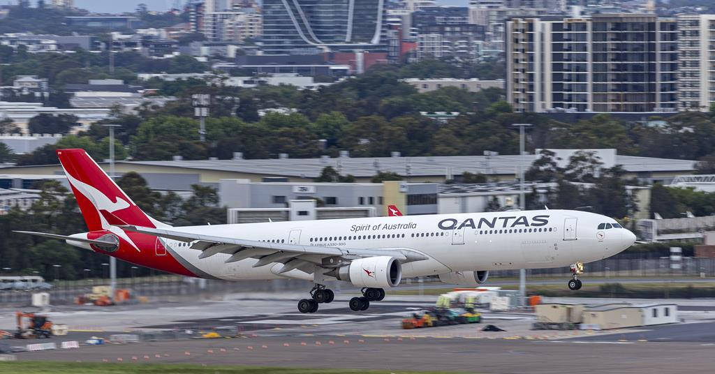 Airport 桌布 壁紙 — 一架澳洲航空空中巴士A330，紅色機尾帶有「Spirit of Australia」塗裝，在跑道上滑行，背景是現代城市建築和綠樹。
