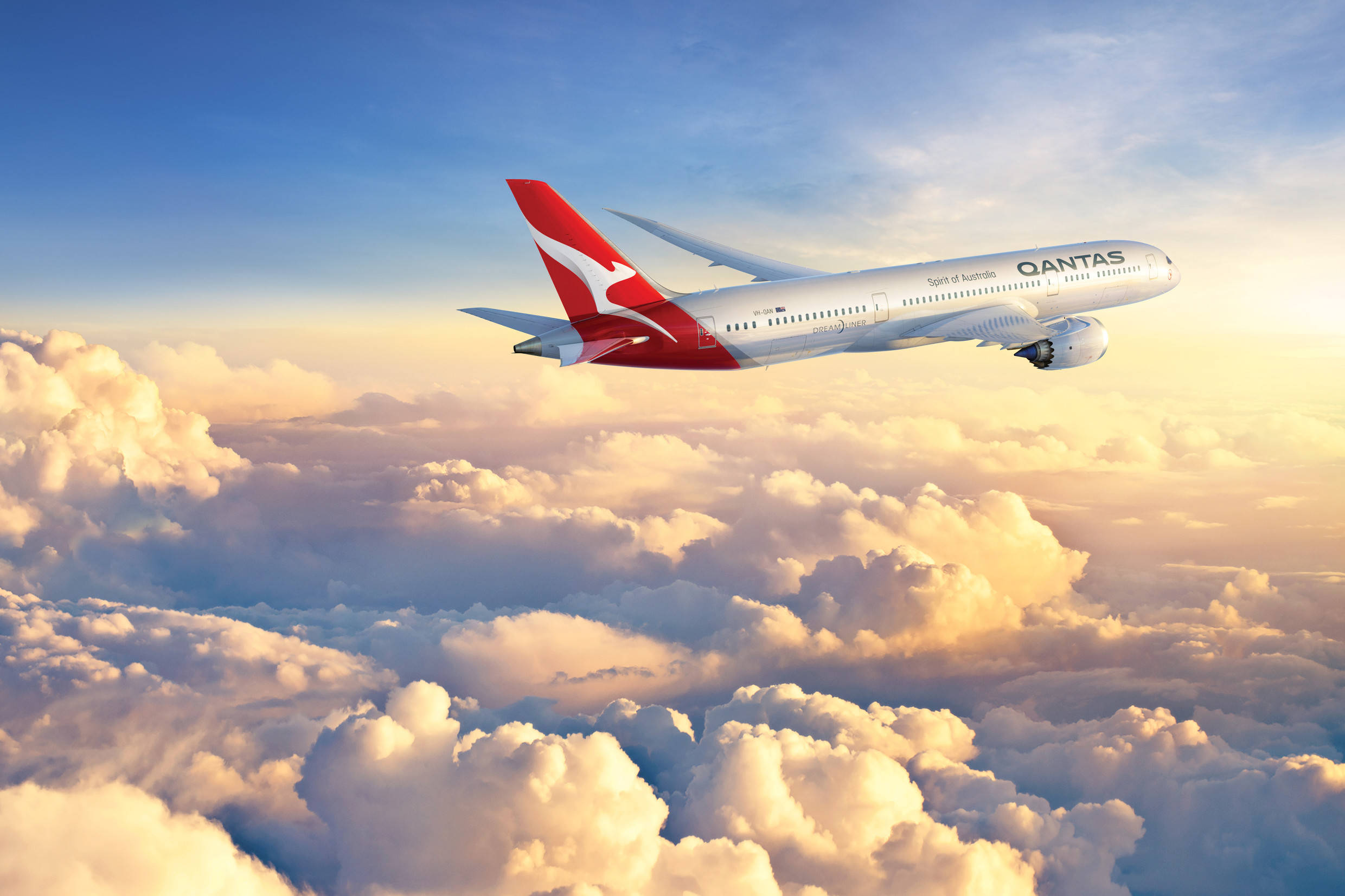 飛機 桌布 壁紙 — 一架澳洲航空飛機在沐浴著金色日落光芒的蓬鬆雲海之上優雅翱翔。
