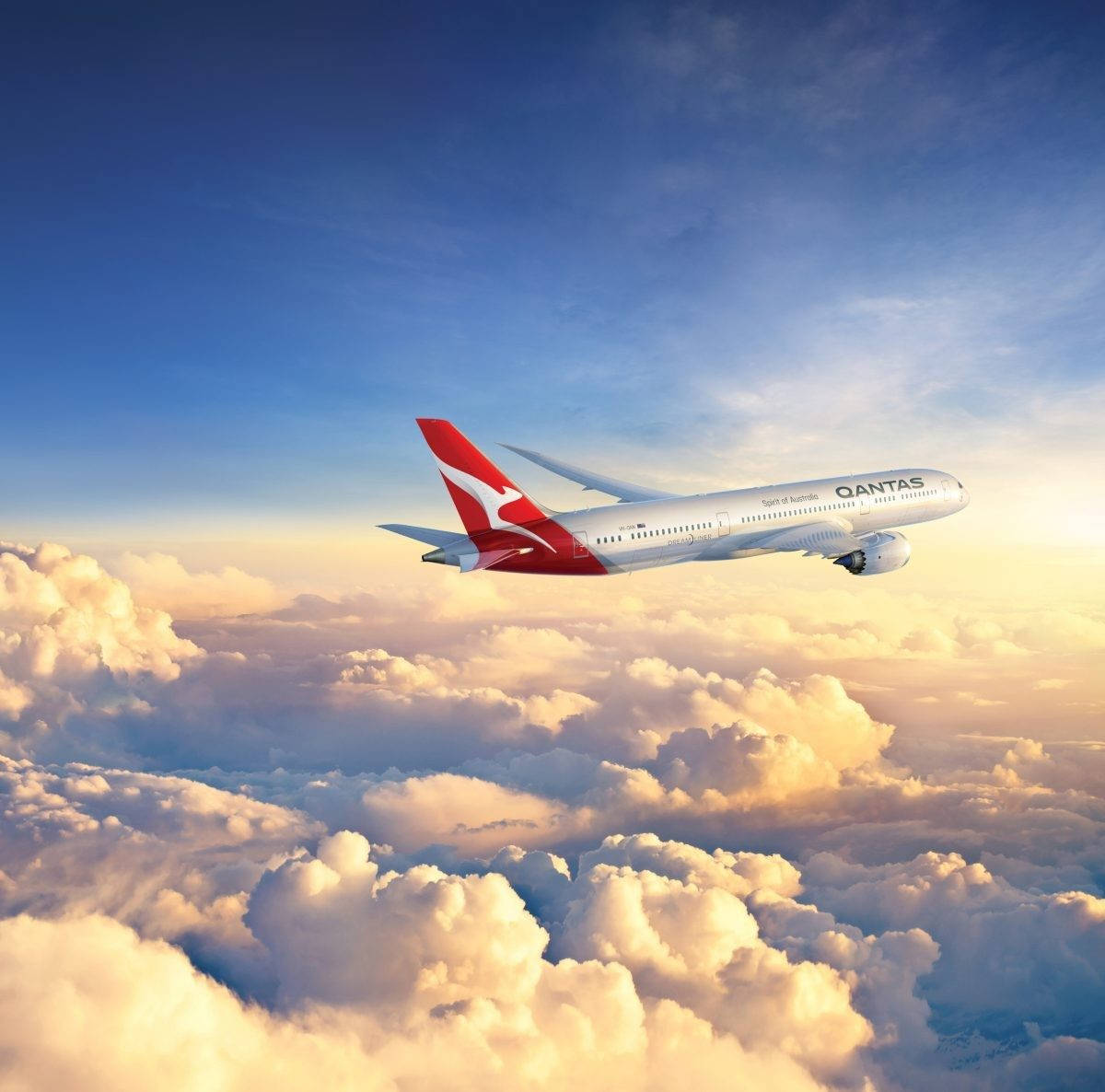 飛機 桌布 壁紙 — 一架澳洲航空飛機在深藍色天空的襯托下，優雅地翱翔於沐浴在金色夕陽光芒中的蓬鬆雲層之上。