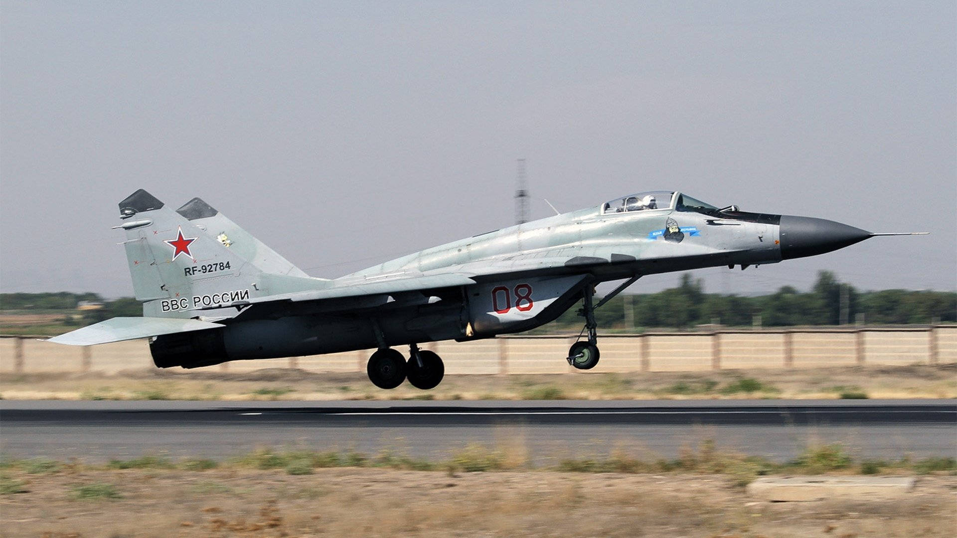 Jets 桌布 壁紙 — 一架灰色俄羅斯MiG-29戰鬥機帶有紅色星標誌，從跑道起飛，背景是朦朧的天空。