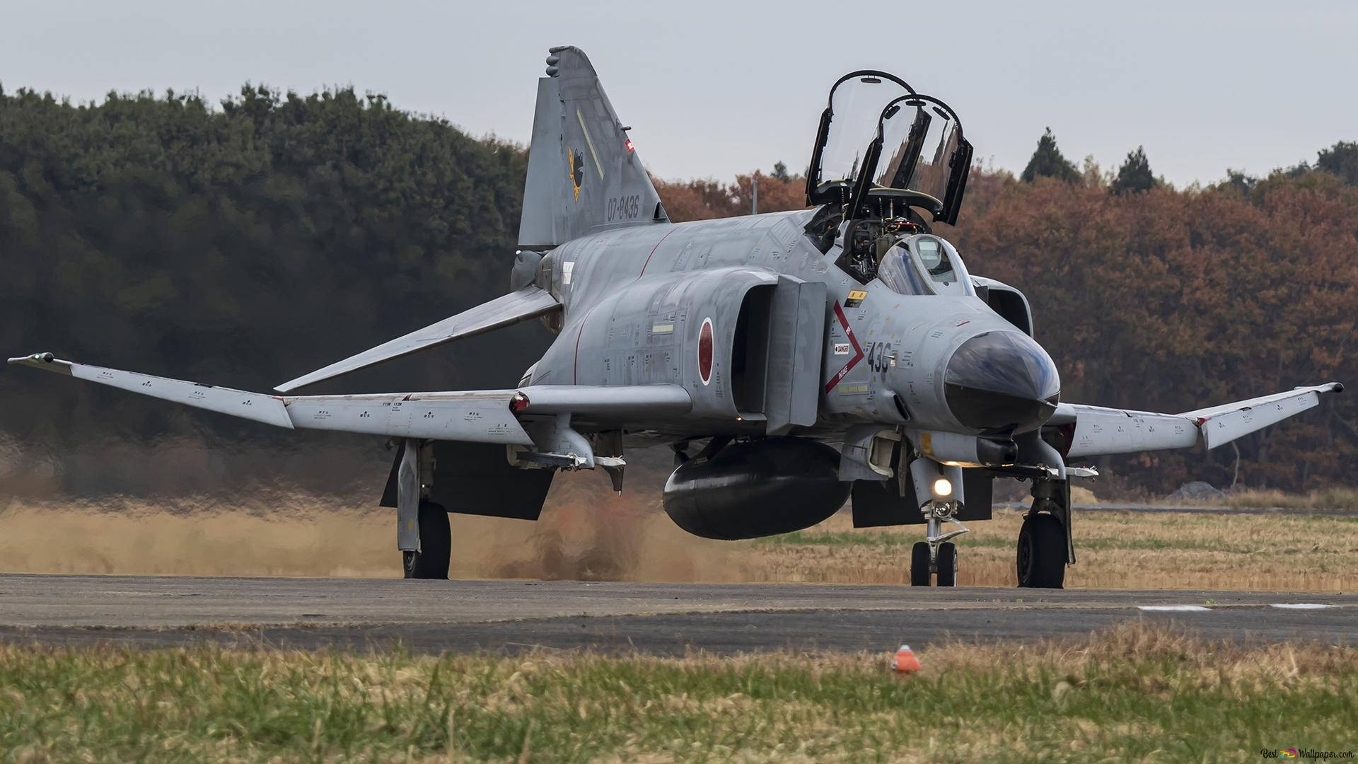 Jets 桌布 壁紙 — 一架灰色日本戰鬥機在跑道上滑行，揚起灰塵，背景是秋天的樹木。