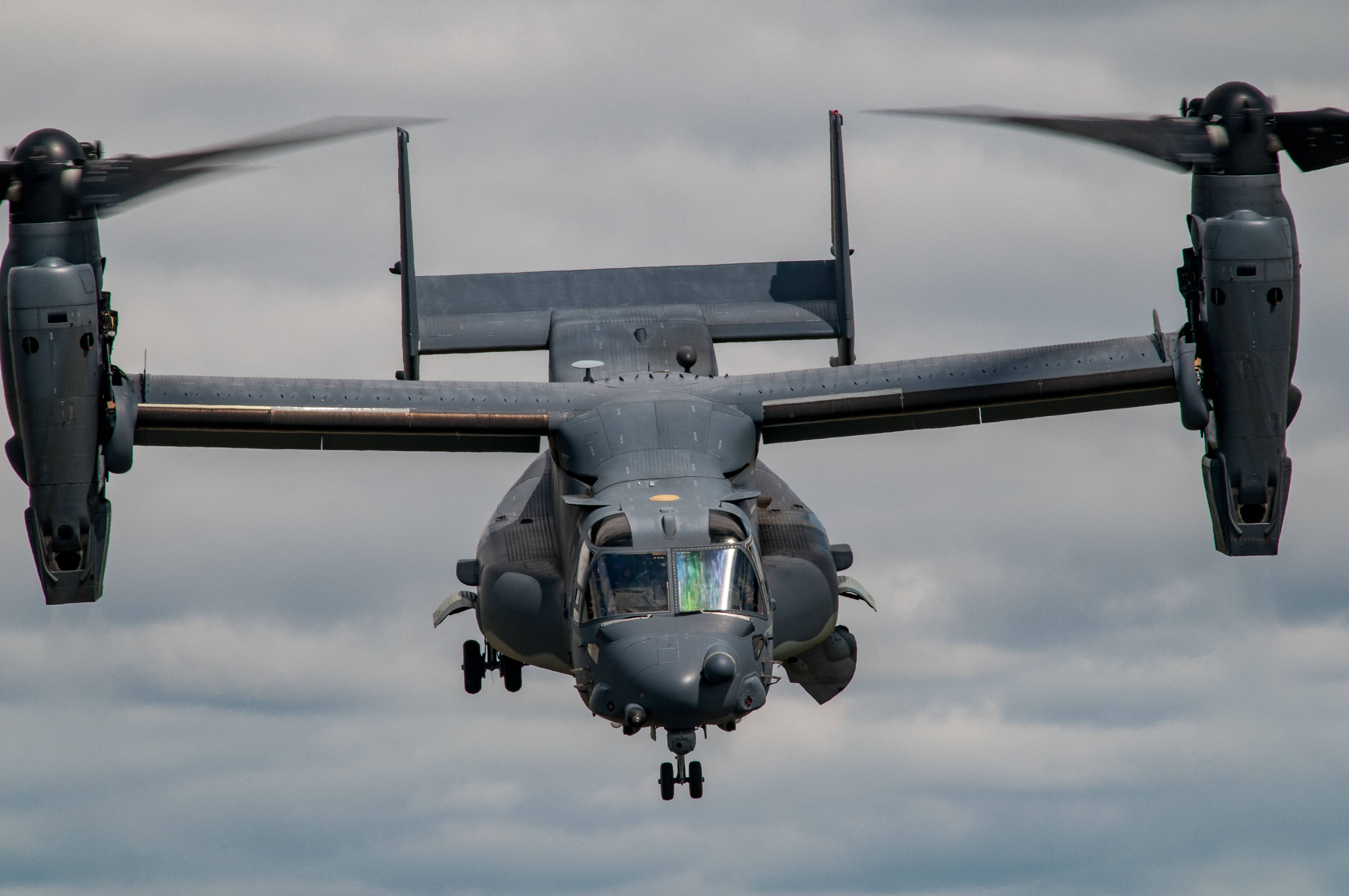 Helicopter 桌布 壁紙 — 一架灰色軍用傾轉旋翼機正面飛向多雲的天空，旋翼旋轉，起落架放下。