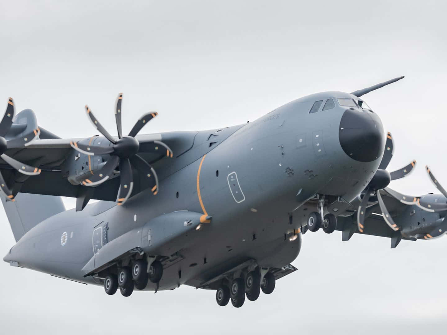 Aircraft 桌布 壁紙 — 一架灰色軍用運輸機，帶有四個大型螺旋槳，在多雲的天空下低飛，起落架已放下。