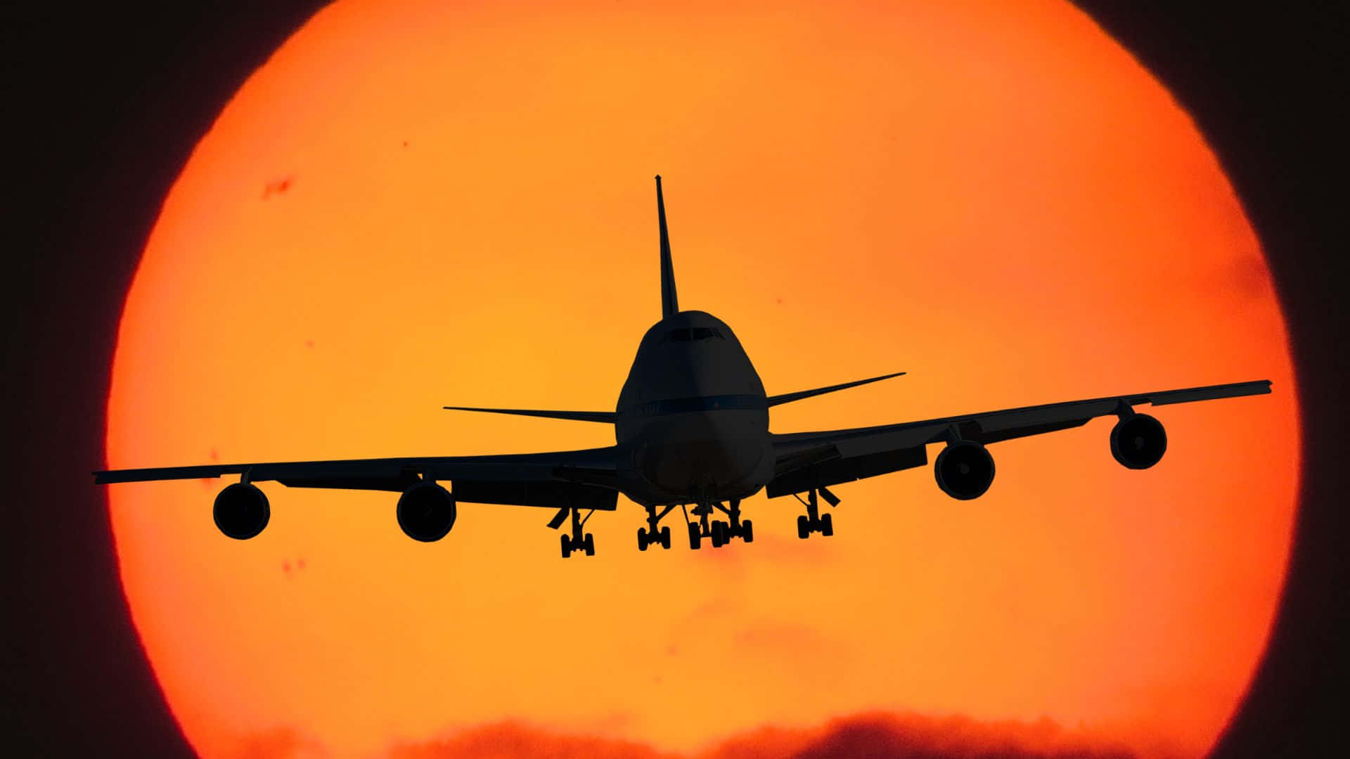  壁紙 — 一架珍寶客機在日落時分以巨大的火橙色太陽為背景形成剪影。