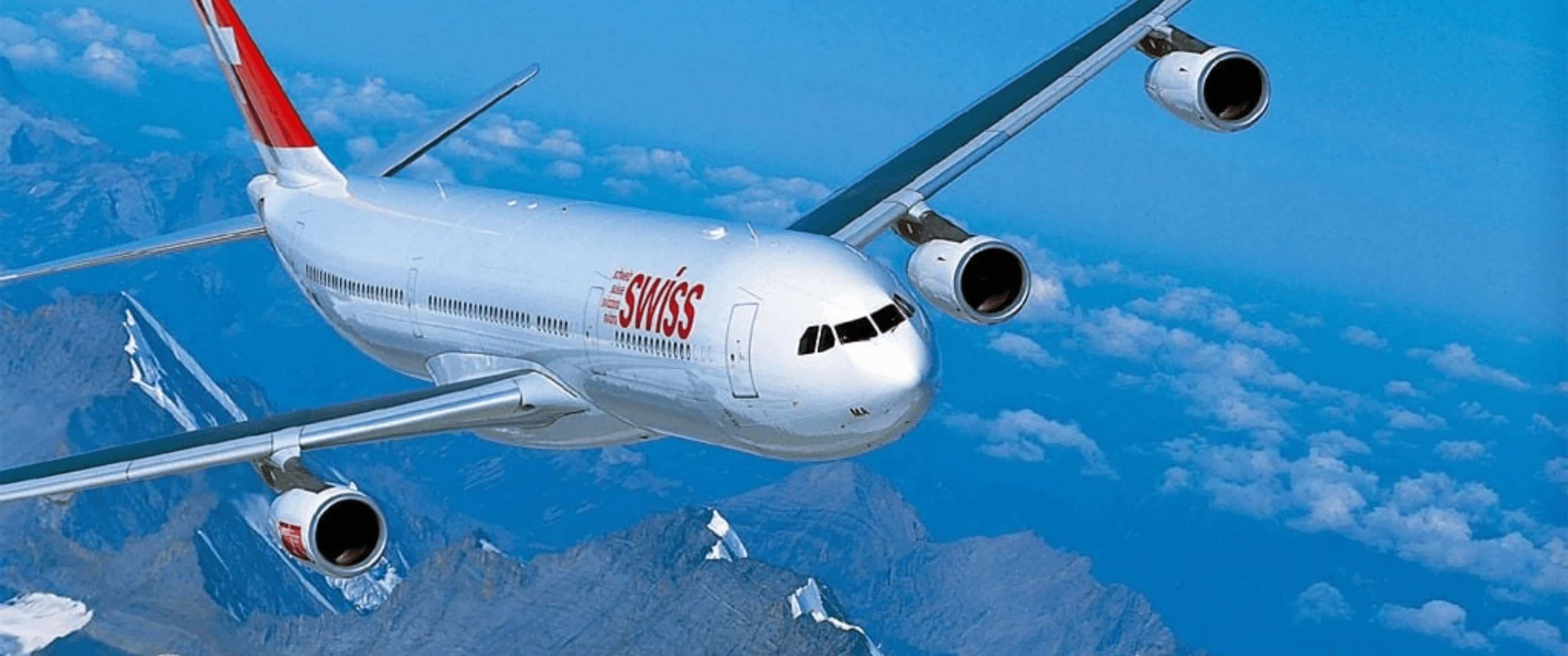 Plane 桌布 壁紙 — 一架瑞士航空的空中巴士A340在點綴著蓬鬆白雲的明亮藍天下，翱翔於積雪覆蓋的山脈之上。