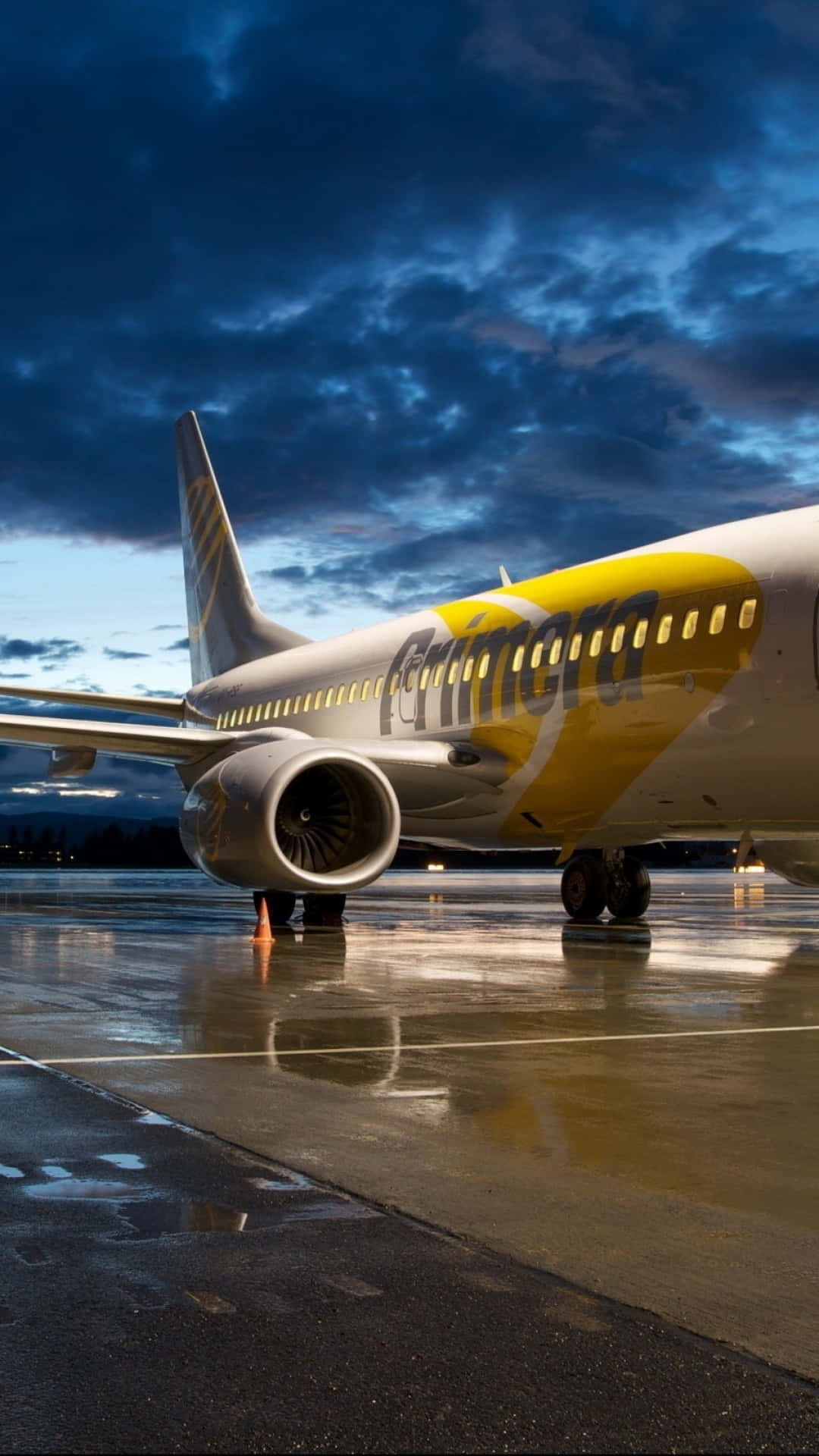 桌布 壁紙 — 一架瑞安航空飛機停在濕滑的停機坪上，背景是戲劇性的暮色天空，烏雲密佈，跑道燈光閃爍。