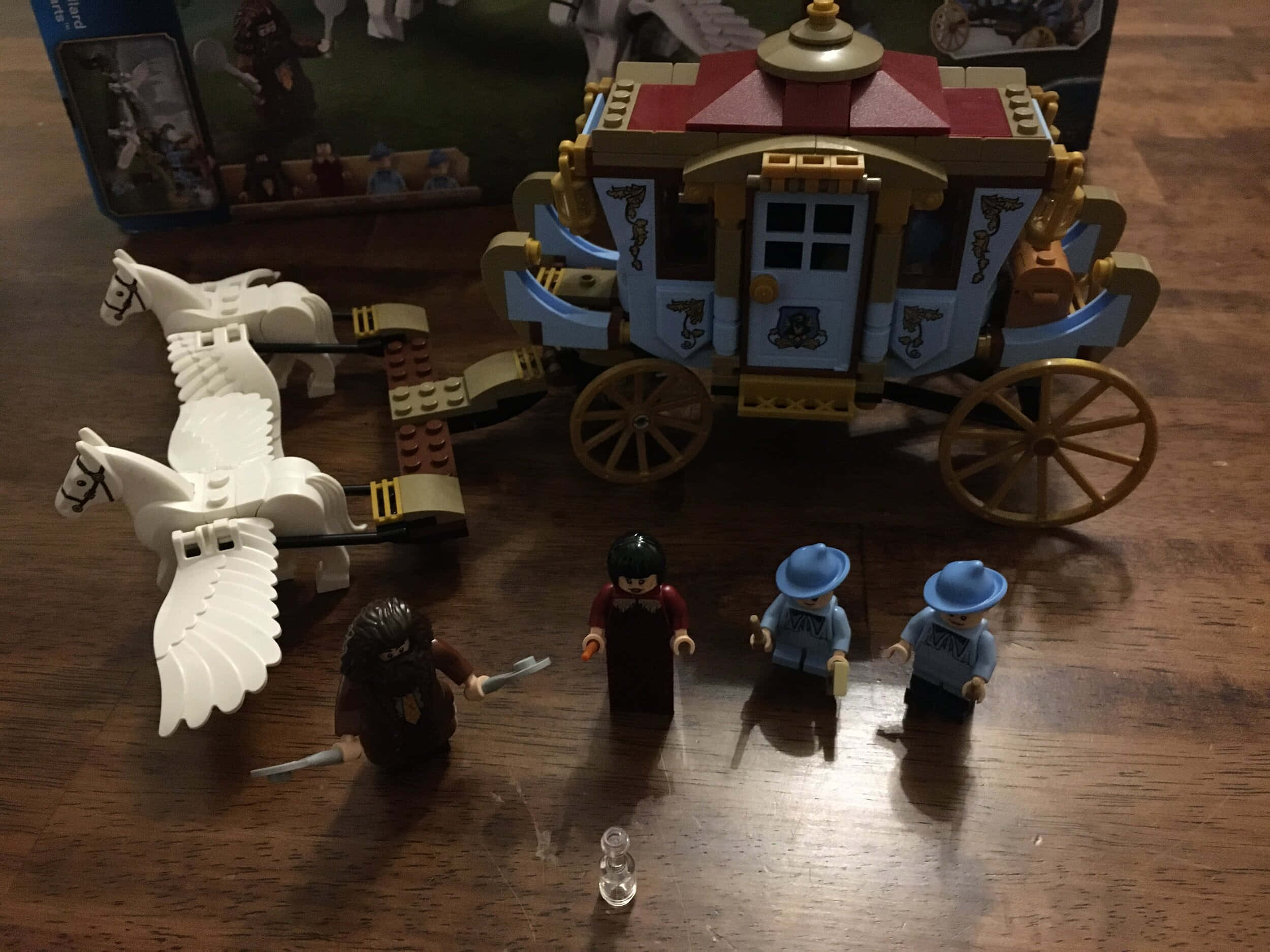 The Hogwarts Carriage 桌布 壁紙 — 一架由白色飛馬拉動的LEGO哈利波特飛行馬車，附有迷你人偶，置於木桌上。