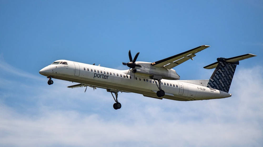 飛機 桌布 壁紙 — 一架白色Porter Airlines渦輪螺旋槳飛機，起落架放下，在晴朗藍天和薄雲中飛行。