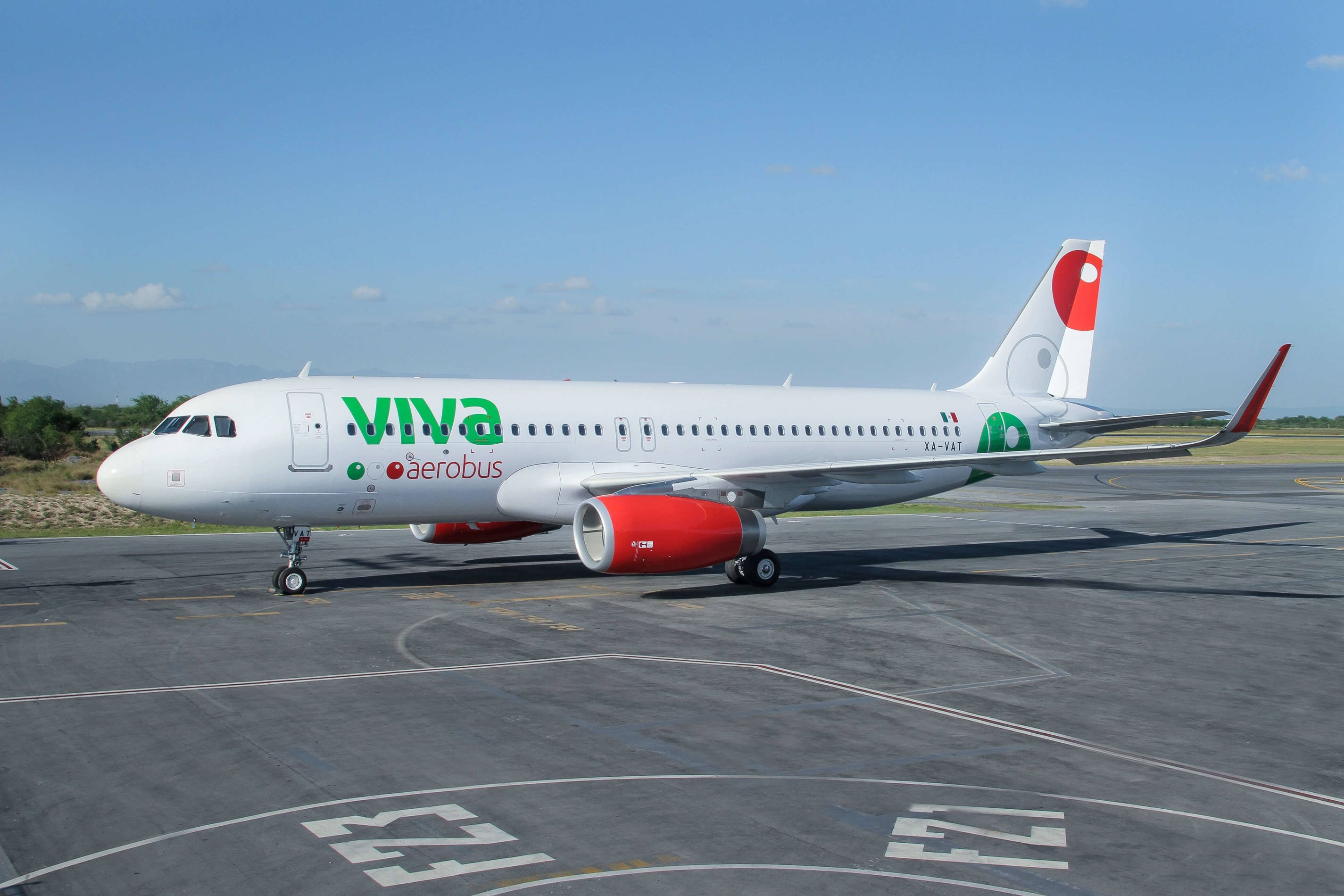飛機 桌布 壁紙 — 一架白色Viva Aerobus空中巴士噴射機，配備紅色引擎，停在陽光明媚的機場停機坪上，天空清澈湛藍。