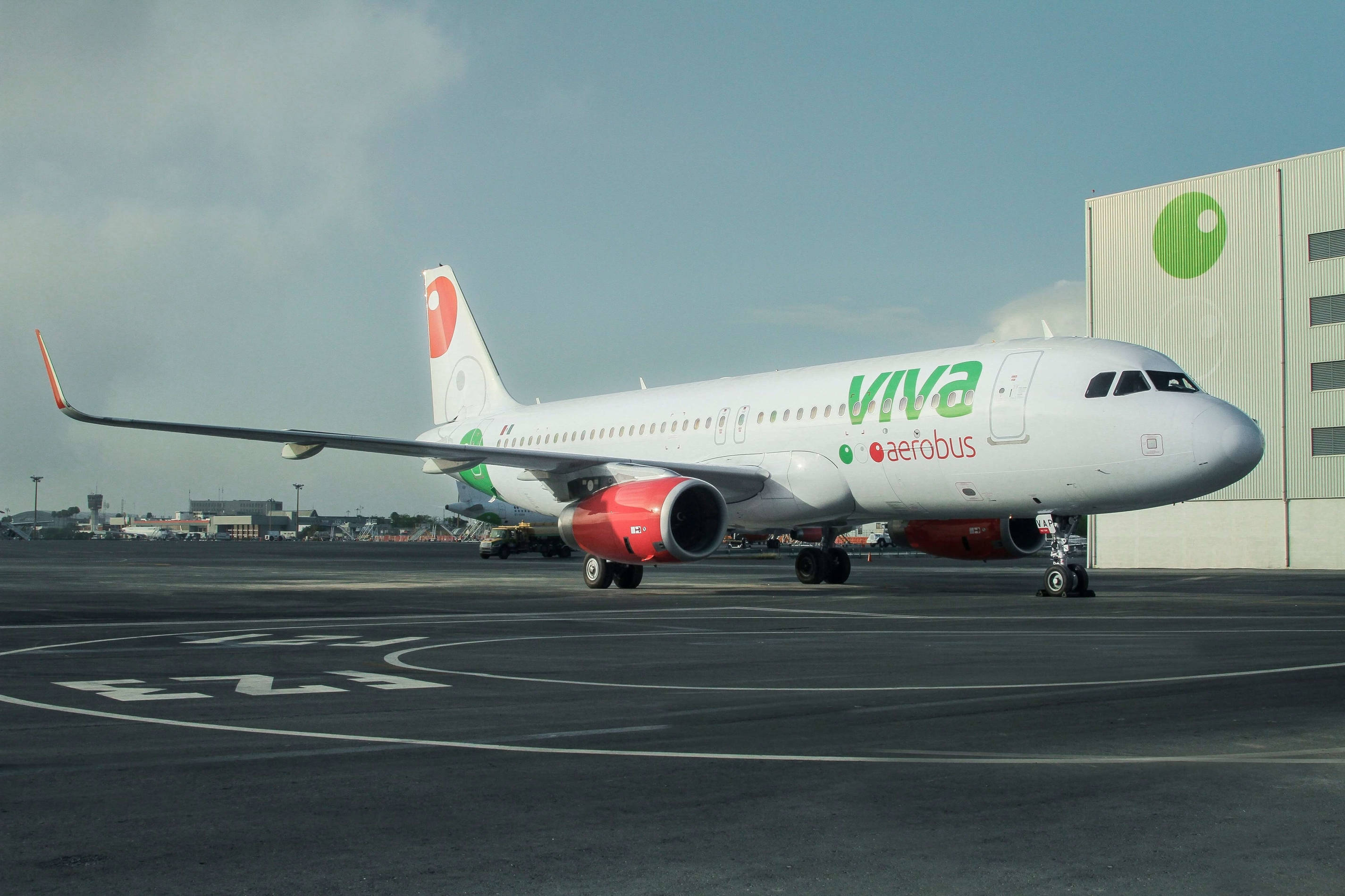 Airport 桌布 壁紙 — 一架白色Viva Aerobus空中巴士A320，配備紅色引擎，在陰天下滑行至機庫附近的停機坪。