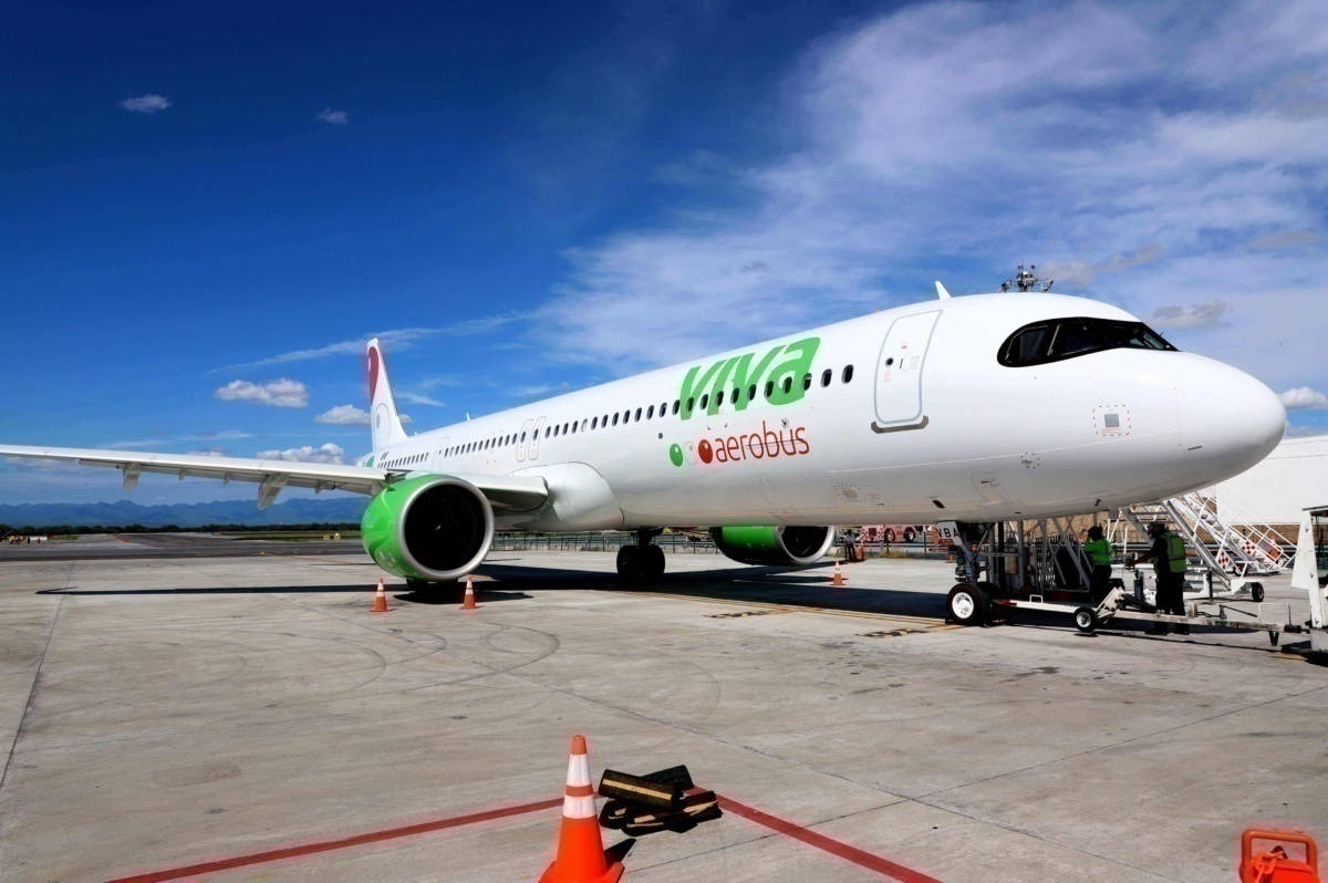 飛機 桌布 壁紙 — 一架白色Viva Aerobus飛機，配備綠色引擎，停在陽光明媚的停機坪上，天空湛藍，雲朵稀疏。