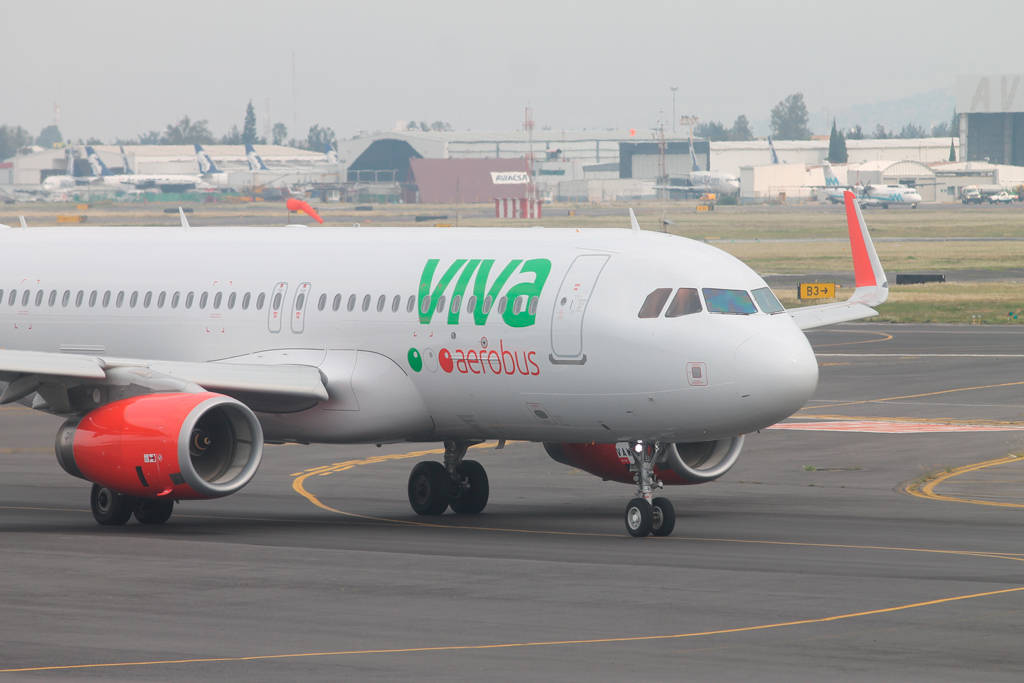 Airport 桌布 壁紙 — 一架白色Viva Aerobus空中巴士噴射機，配備紅色引擎，在陰天的灰色機場停機坪上滑行。