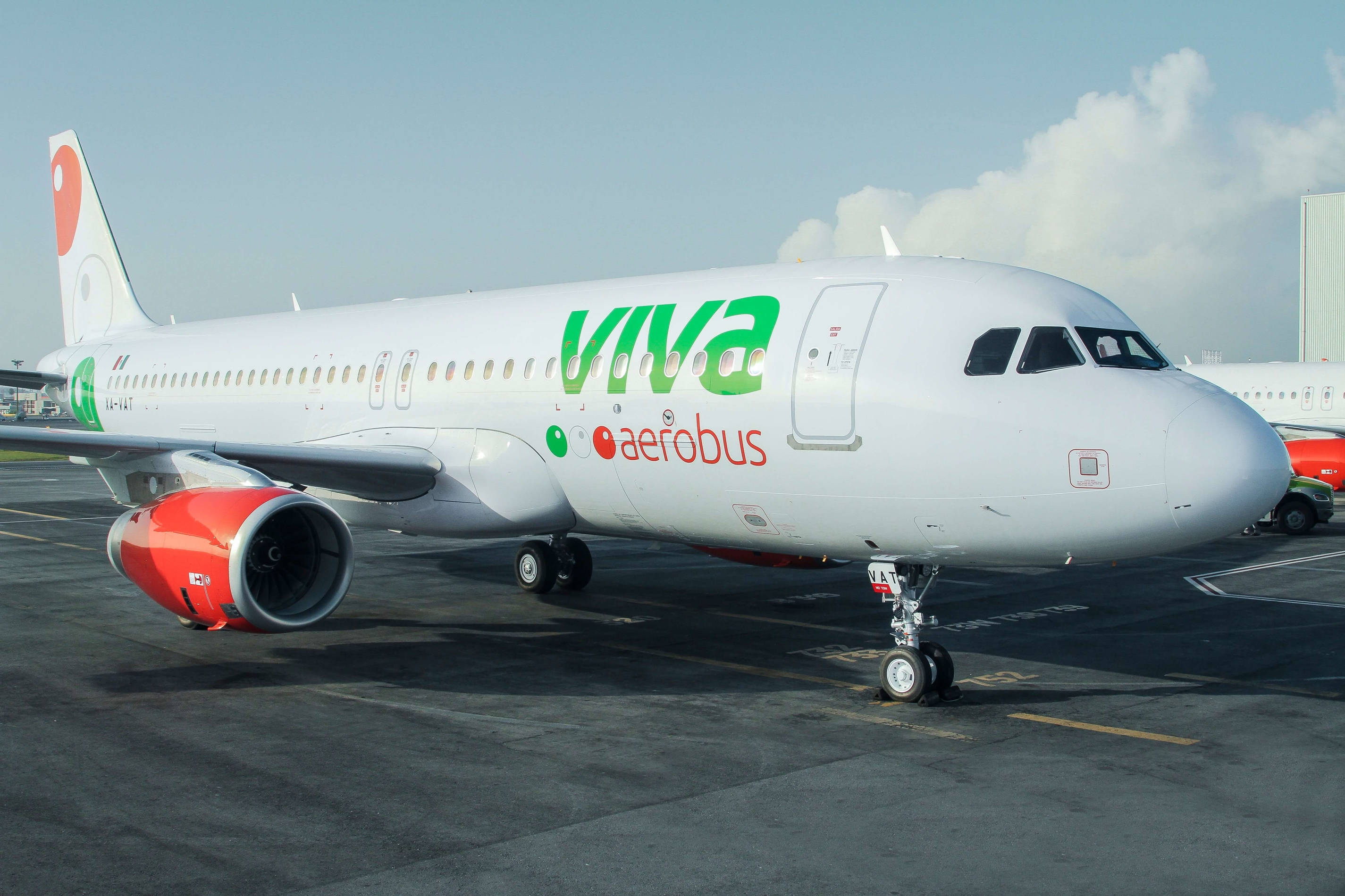 飛機 桌布 壁紙 — 一架白色Viva Aerobus Airbus噴射機配備紅色引擎，在明亮的日光下停在機場停機坪上。