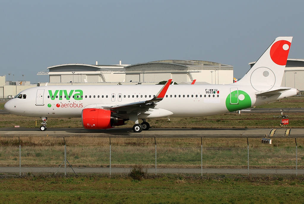 Airport 桌布 壁紙 — 一架白色Viva Aerobus空中巴士A320，配備紅色引擎和綠色品牌標誌，在晴朗天空下於機庫附近的跑道上滑行。
