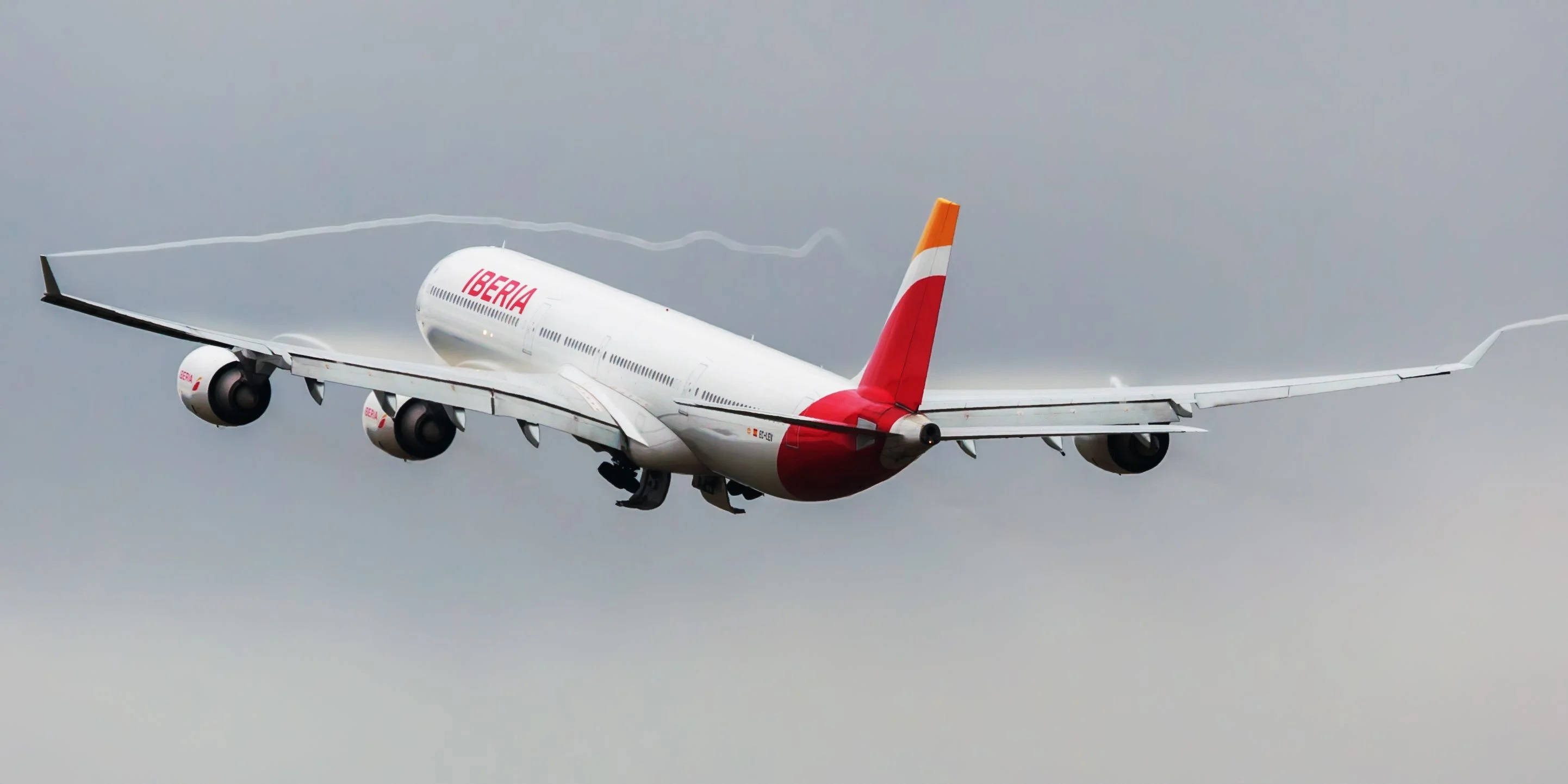 Blue Sky 桌布 壁紙 — 一架白色伊比利亞航空空中巴士A380客機，紅色尾翼，在灰色多雲的天空低飛，留下水蒸氣痕跡。