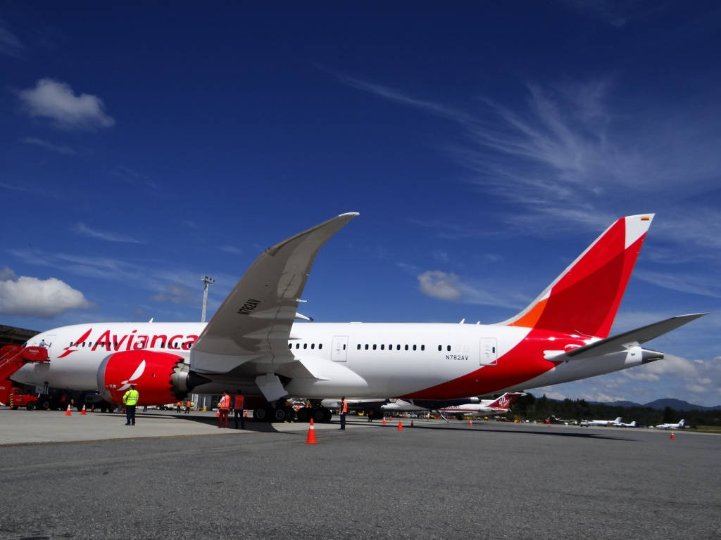 Airport 桌布 壁紙 — 一架白色和紅色的 Avianca 波音 787 夢幻客機停在停機坪上，背景是明亮的藍天和零星的白雲。
