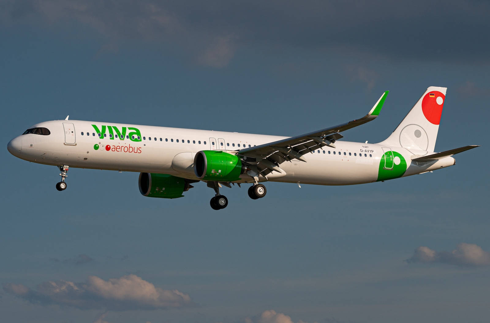 飛機 桌布 壁紙 — 一架白色和綠色的 Viva Aerobus 飛機放下起落架，在藍天白雲中飛行。