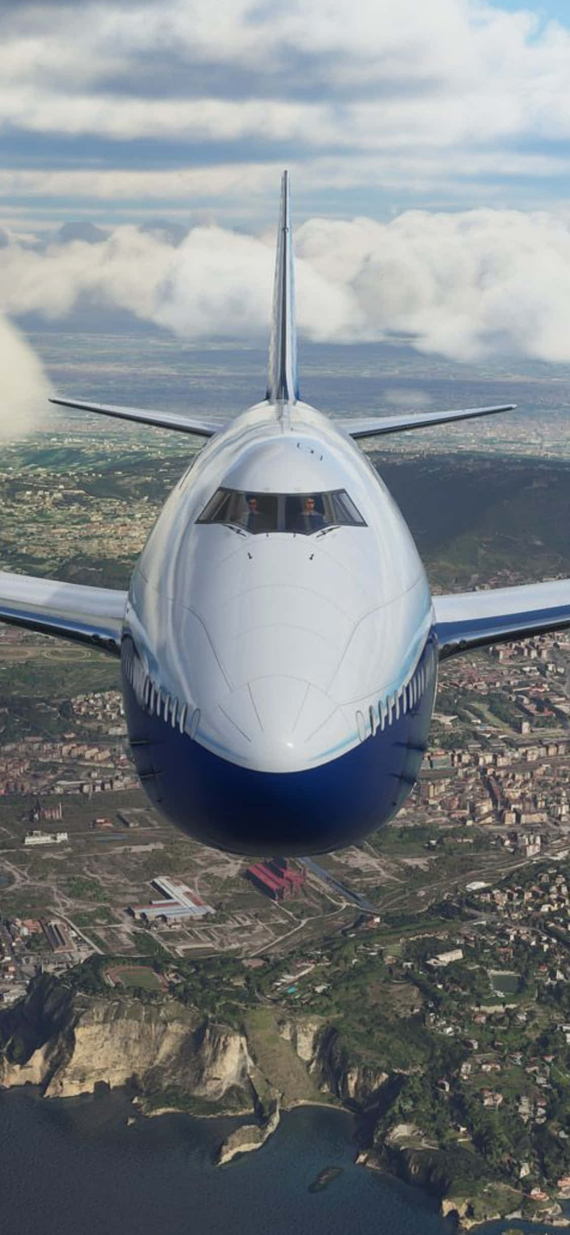 iPhone Xs Microsoft Flight Simulator 桌布 壁紙 — 一架白色和藍色的客機飛過一個有懸崖和雲層的海岸城市上空。