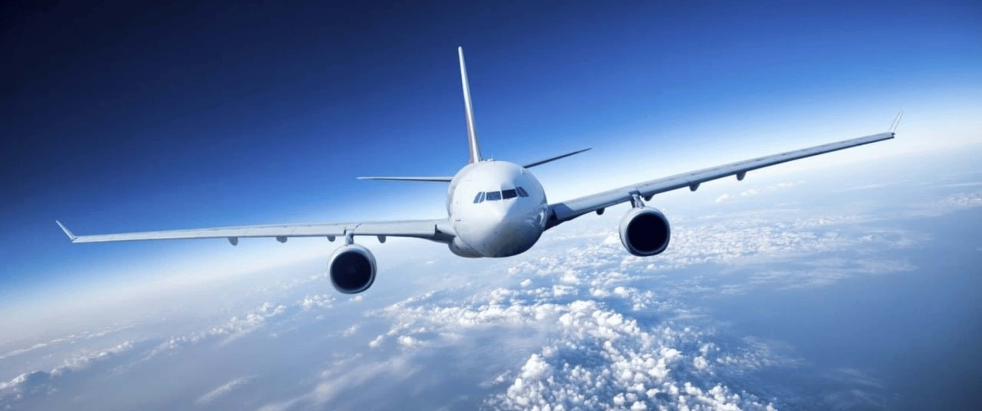 Plane 桌布 壁紙 — 一架白色商用飛機在廣闊清澈的藍天下，翱翔於蓬鬆的白雲之上。