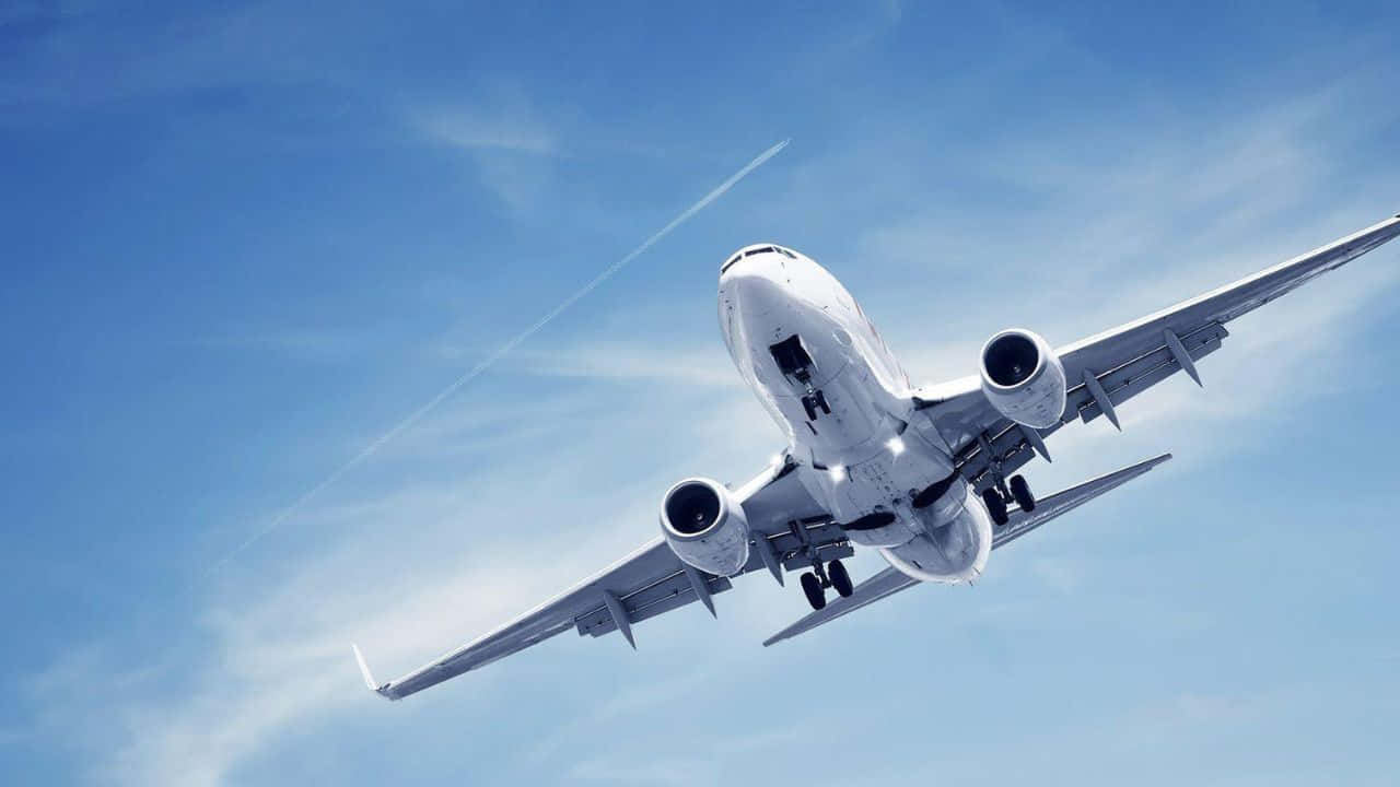 720p Plane 桌布 壁紙 — 一架白色商用飛機在清澈的藍天中向上翱翔，留下一道細細的凝結尾跡。