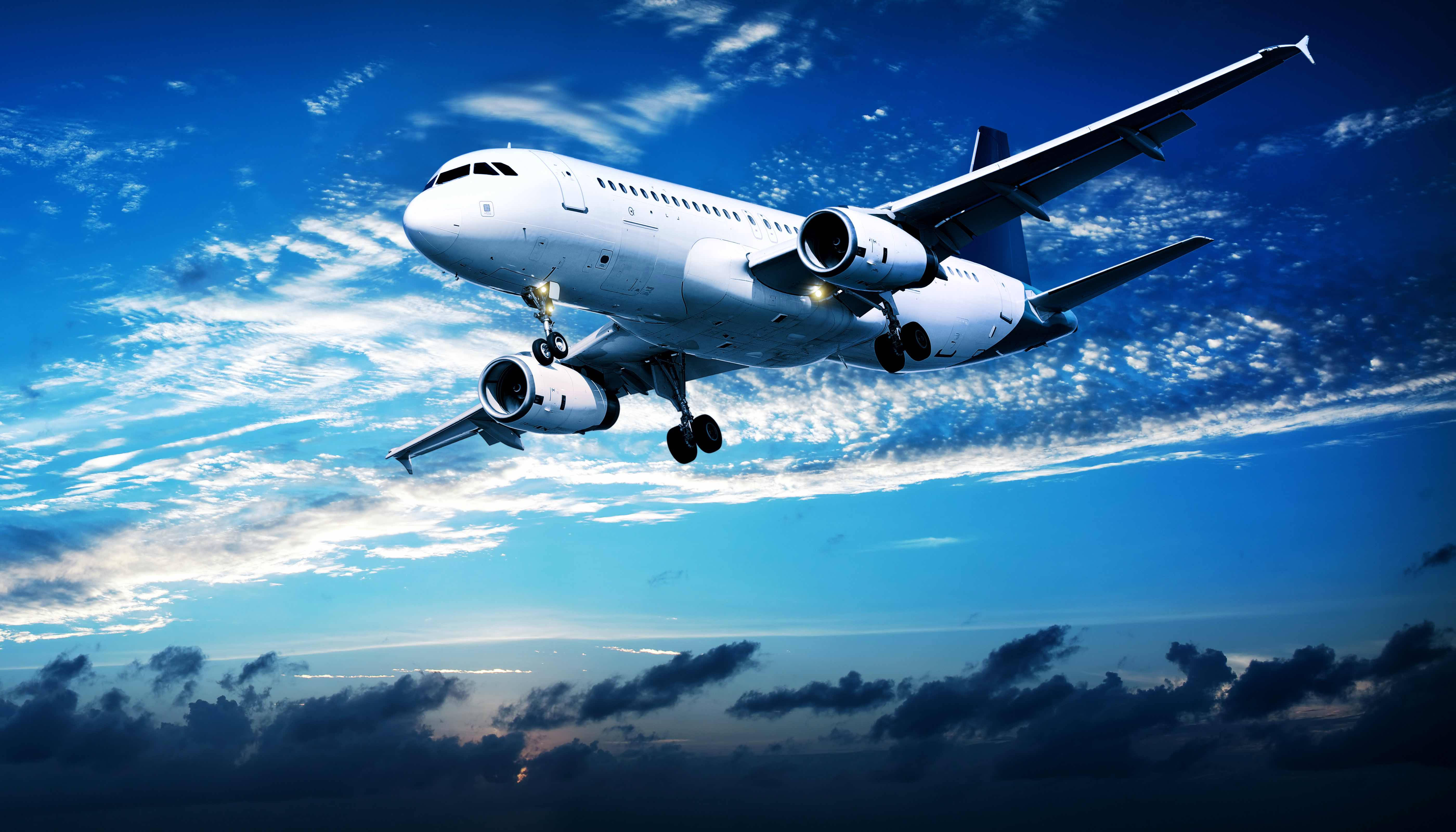 飛機 桌布 壁紙 — 一架白色商用飛機正穿過一條條薄雲和下方黑暗風暴雲的鮮豔藍天下降。