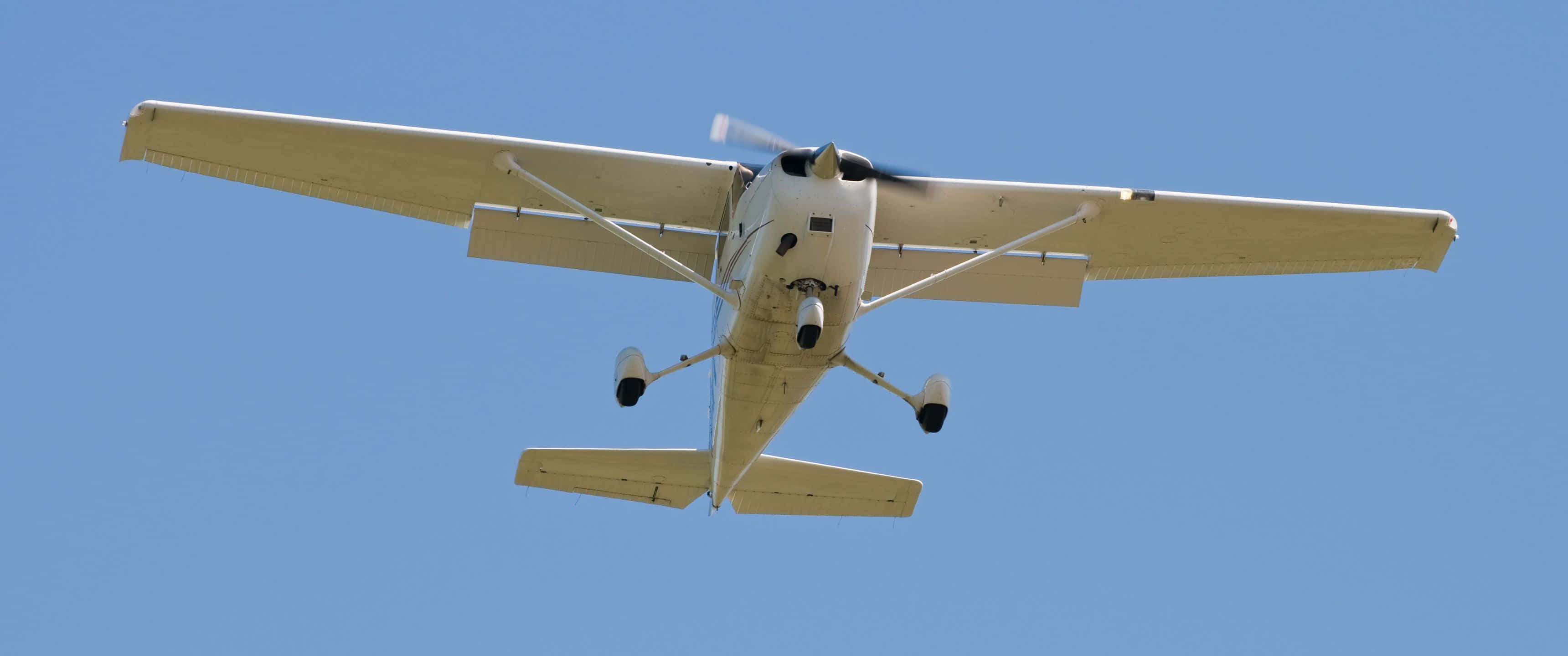3440x1440p Small Planes 桌布 壁紙 — 一架白色單引擎螺旋槳飛機在晴朗的藍天中飛過頭頂。