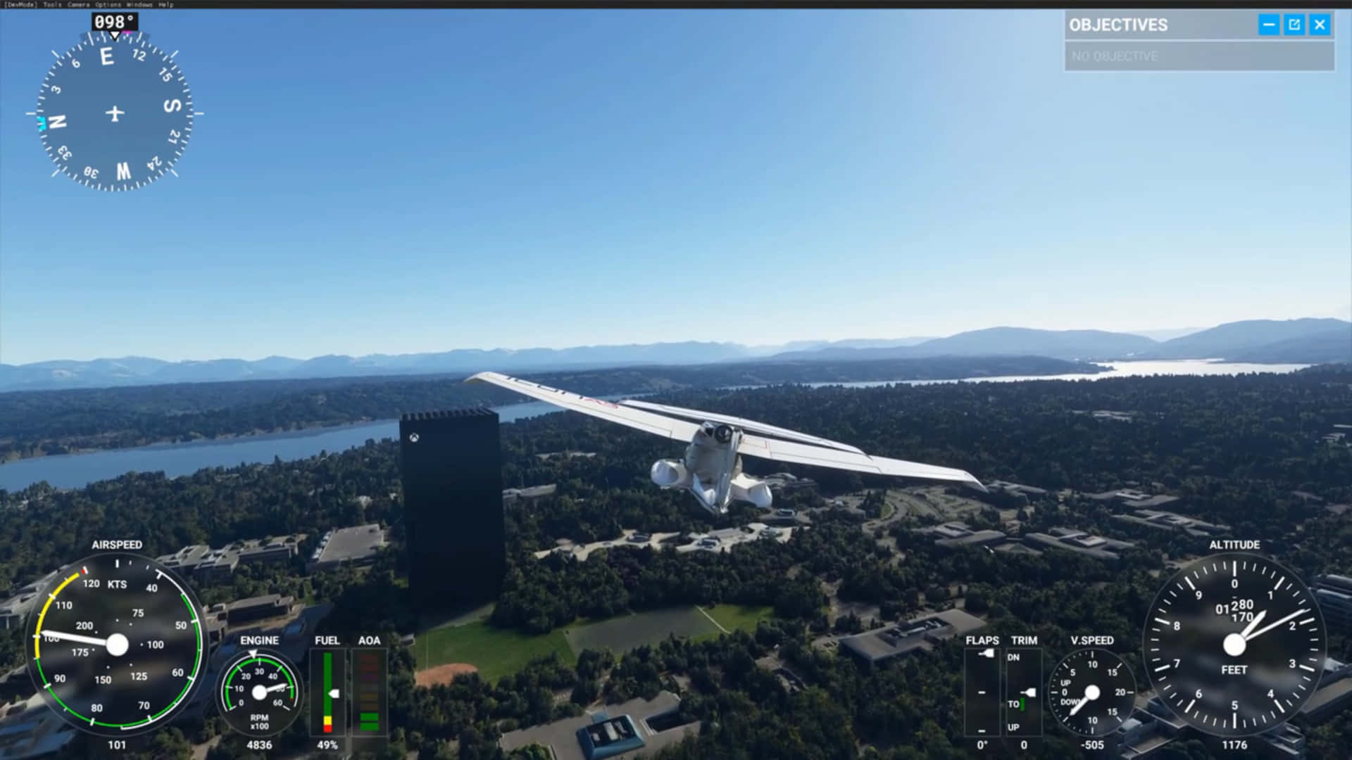 1080p Microsoft Flight Simulator 桌布 壁紙 — 一架白色單引擎飛機在晴朗藍天下，低飛過陽光明媚的郊區景觀，有河流和遠處的山脈。