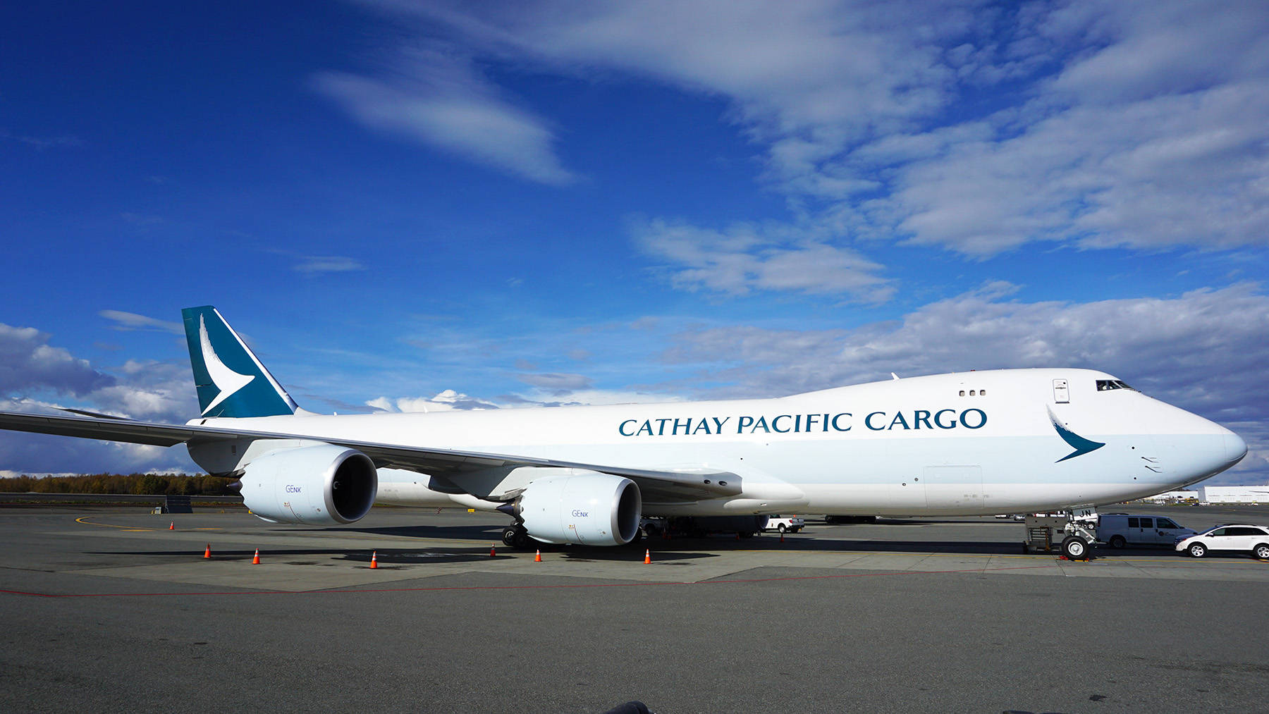 Airport 桌布 壁紙 — 一架白色國泰航空貨運波音747停放在機場停機坪上，天空湛藍，白雲點綴。