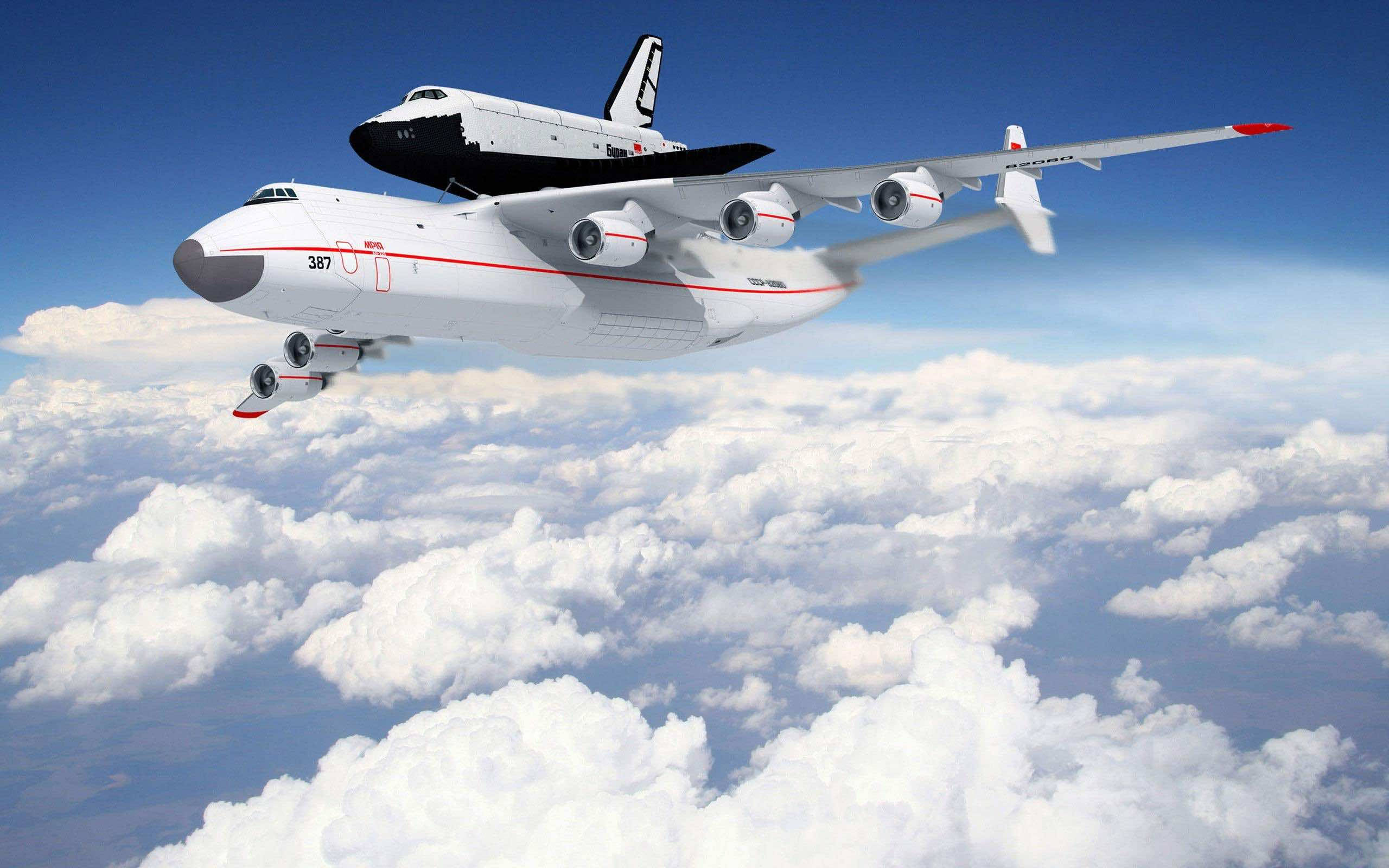 flying 桌布 壁紙 — 一架白色安東諾夫An-225貨機在晴朗藍天下，於蓬鬆白雲之上運載著一架黑白相間的太空梭。