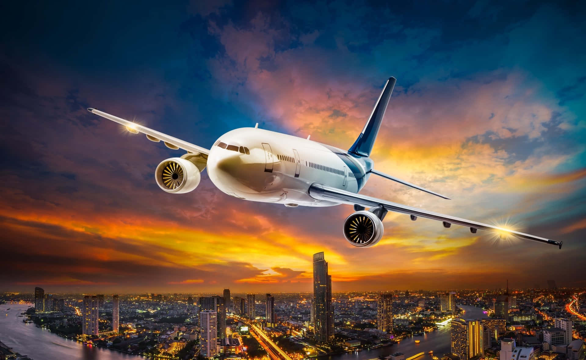 HD Plane 桌布 壁紙 — 一架白色客機在日落時分翱翔於廣闊的城市天際線之上，下方有火紅的橙色雲彩和閃爍的摩天大樓。