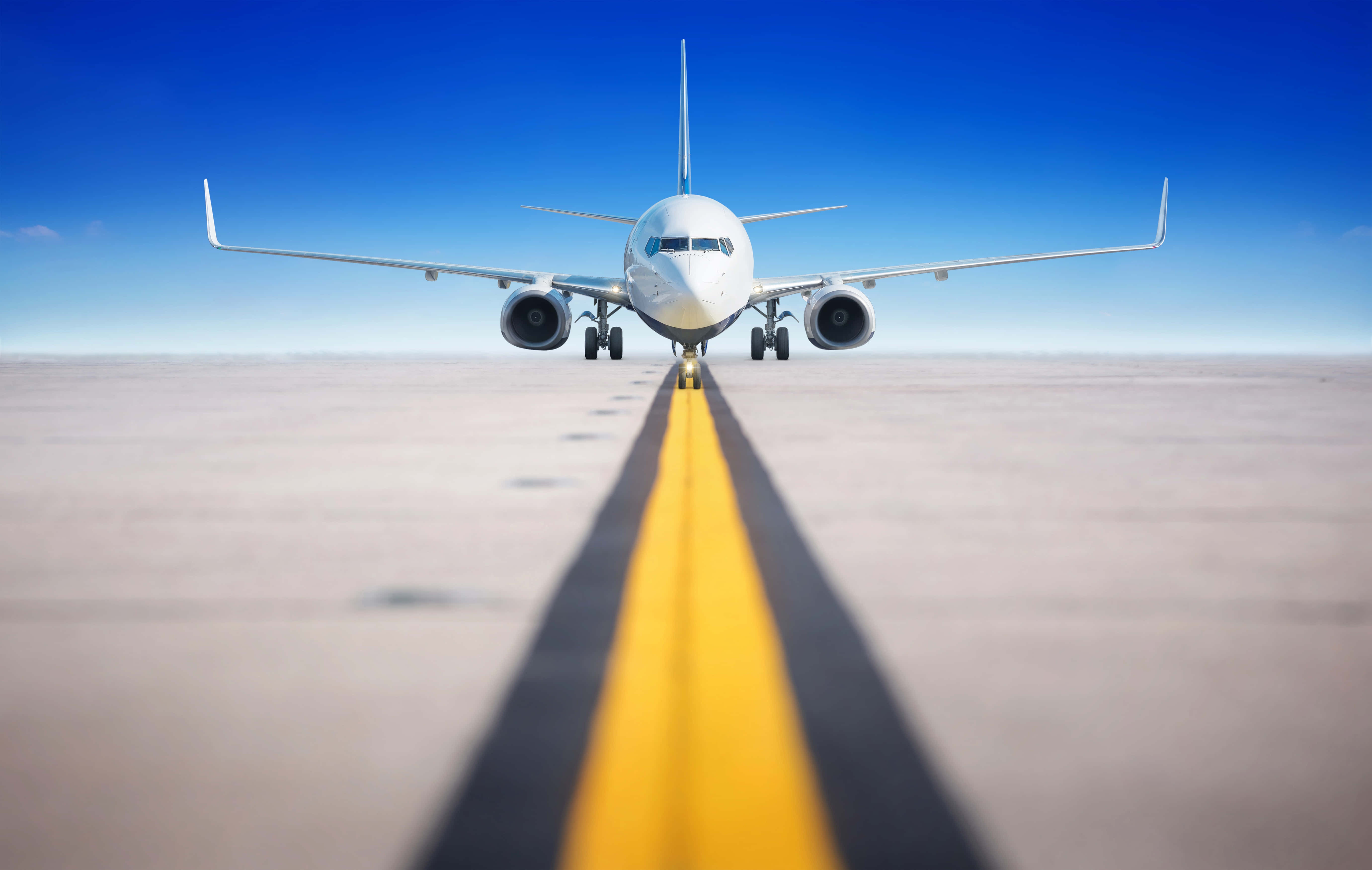 Plane 桌布 壁紙 — 一架白色客機在晴朗藍天下，面向跑道上的一條粗黃色中心線。