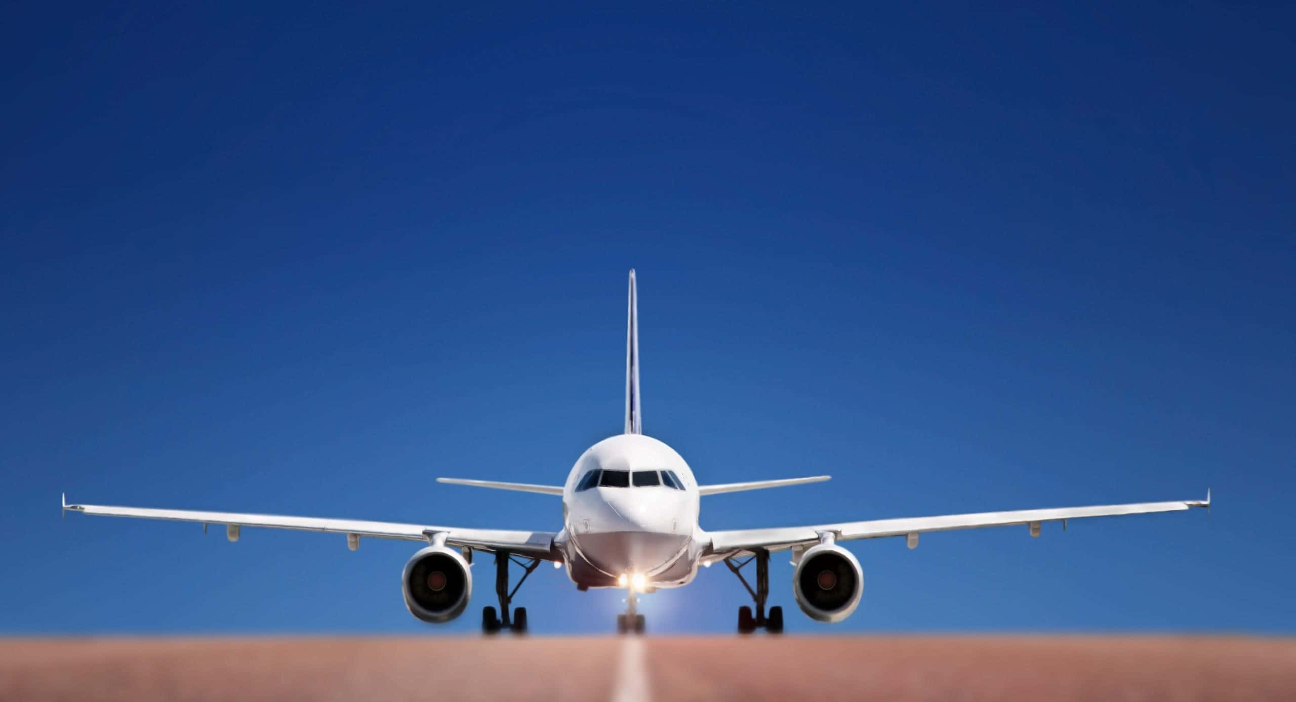 Flight 桌布 壁紙 — 一架白色客機在晴朗藍天和明亮陽光下，在跑道上向前方。