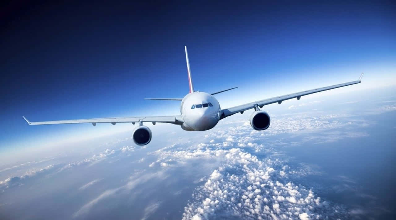 飛機 桌布 壁紙 — 一架白色客機在深藍色天空下翱翔於蓬鬆的白雲之上。