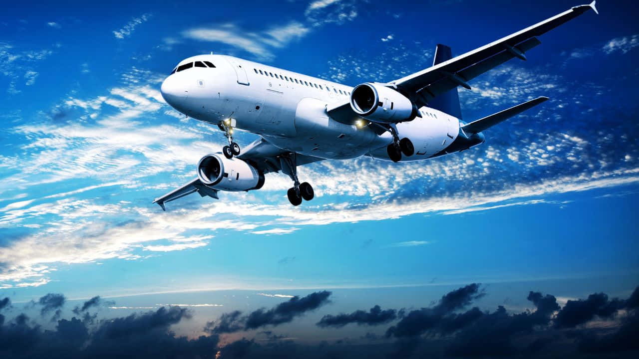 720p Plane 桌布 壁紙 — 一架白色客機在湛藍的天空中翱翔，伴隨著散落的雲朵和發光的引擎。