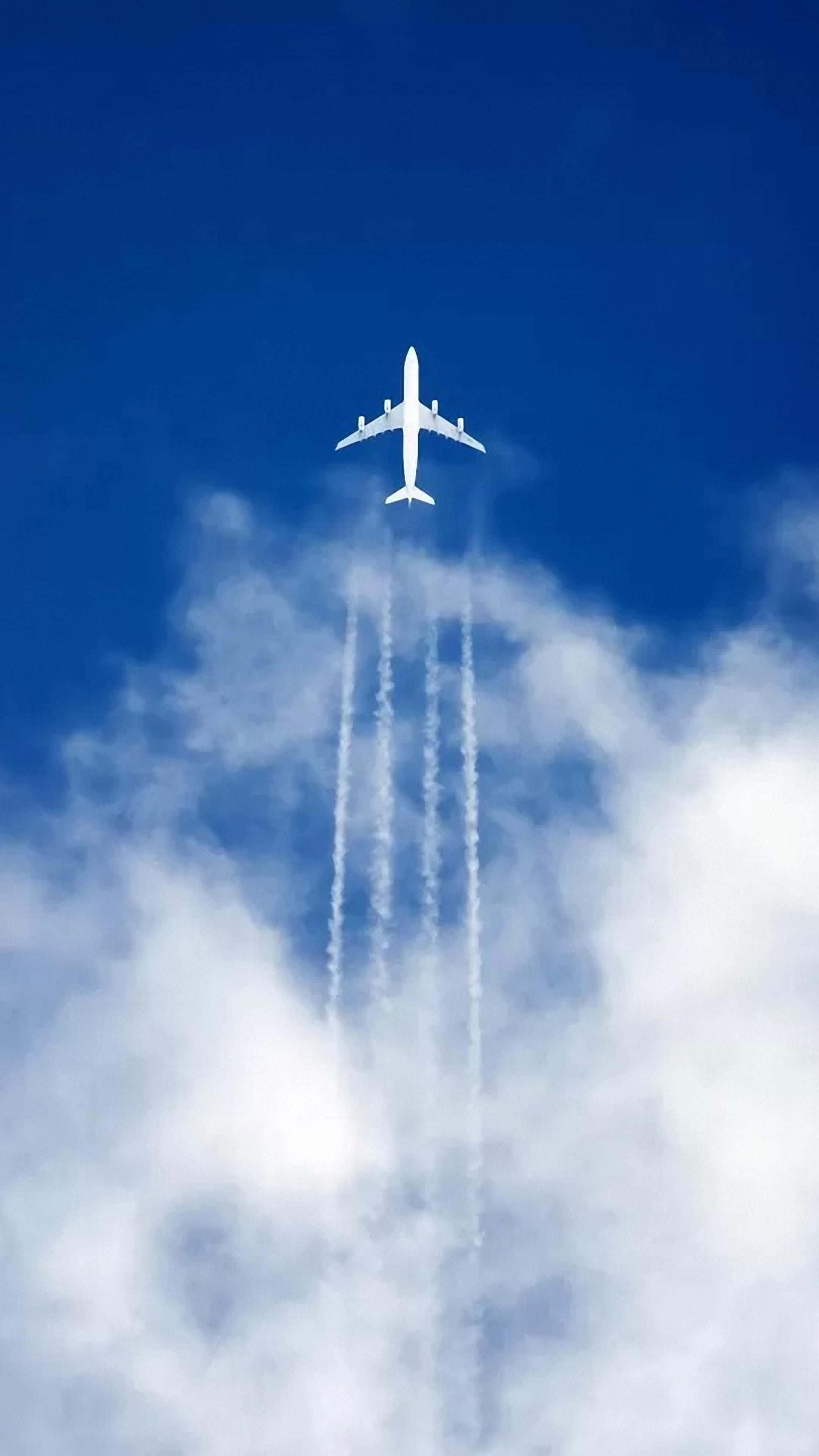 天空 桌布 壁紙 — 一架白色客機在鮮豔的藍天中翱翔，攀升到蓬鬆的白雲之上，留下四條清晰的凝結尾跡。