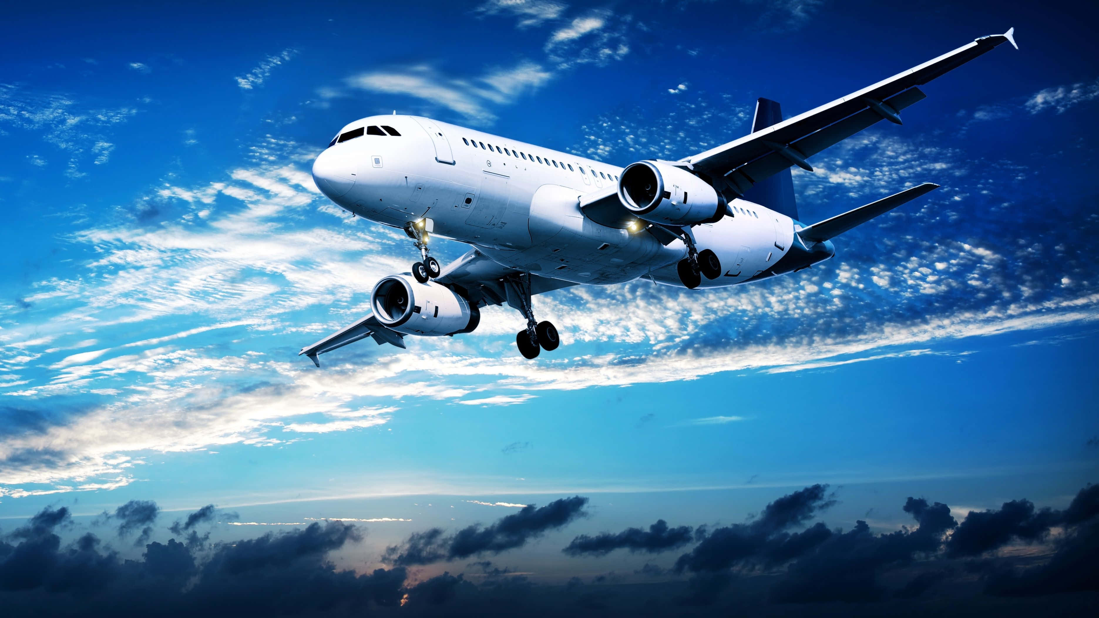 Plane 桌布 壁紙 — 一架白色客機穿過佈滿縷縷白雲和下方黑暗雲層的鮮豔藍天下降。