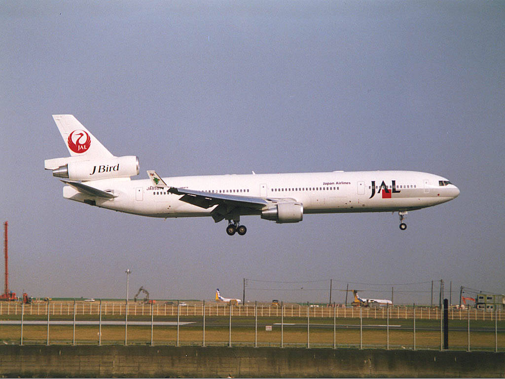 日本 桌布 壁紙 — 一架白色日本航空波音767，帶有紅色標誌，在朦朧的天空下從機場跑道起飛。