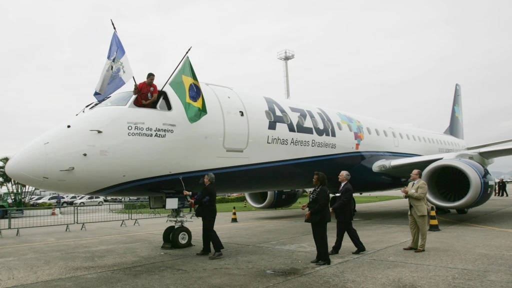 巴西 桌布 壁紙 — 一架白色的Azul Airlines飛機，駕駛艙上有巴西和宏都拉斯國旗，人們在陰天時在附近走動。
