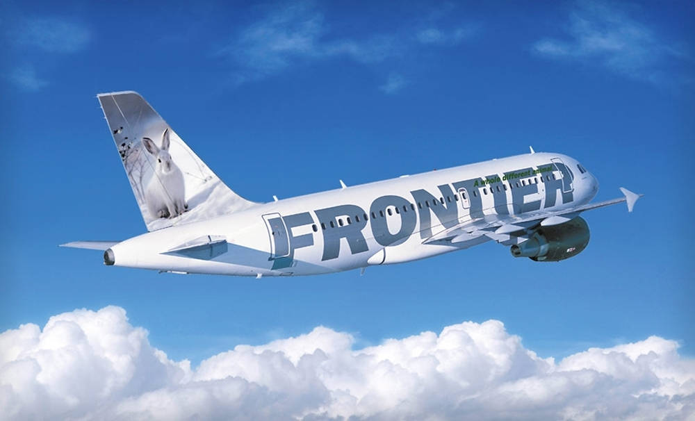  壁紙 — 一架白色的Frontier Airlines飛機在鮮豔的藍天背景下翱翔於蓬鬆的白雲之上。
