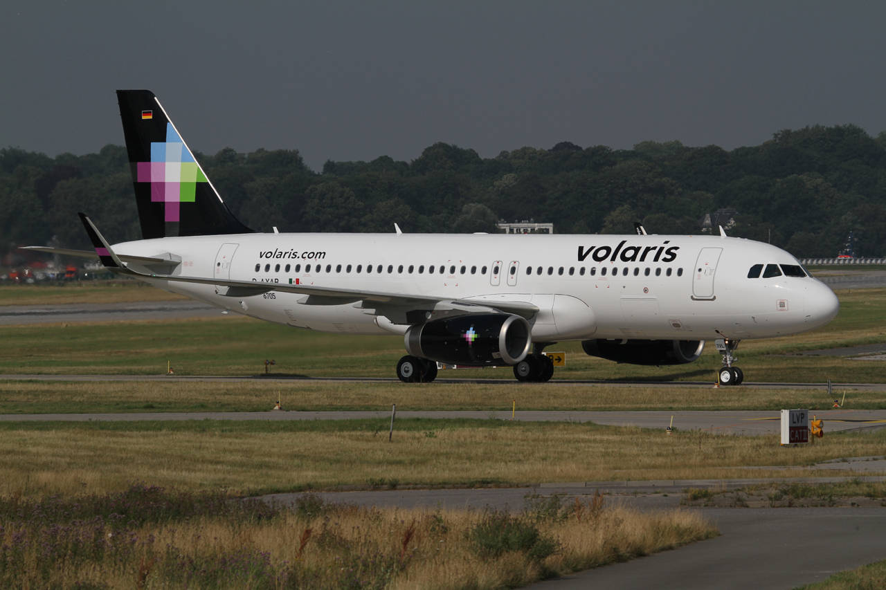 transportation 桌布 壁紙 — 一架白色的Volaris空中巴士A320在跑道上滑行，背景是黑暗的天空和綠樹。