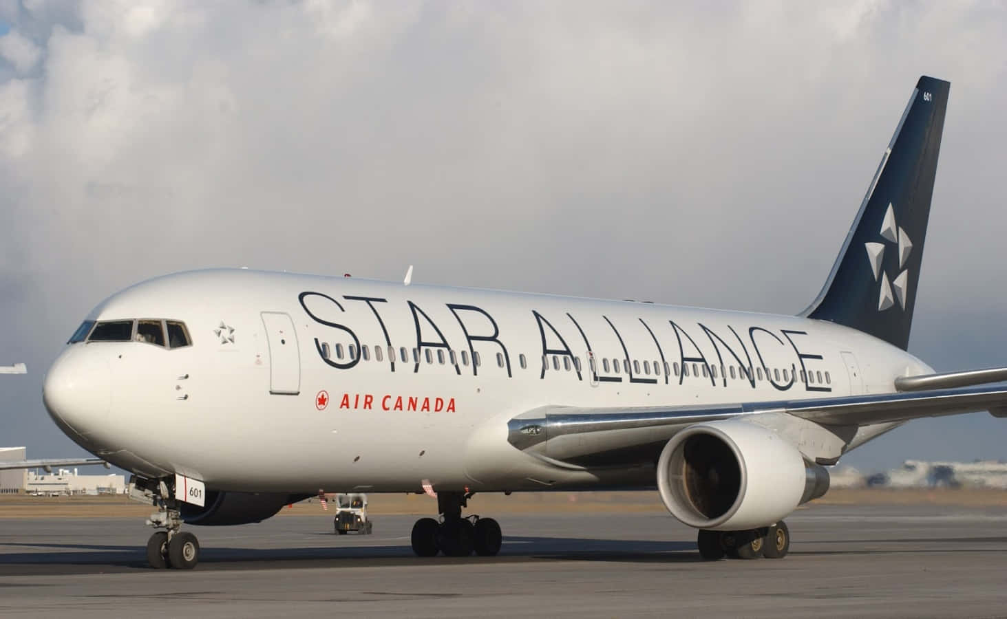 飛機 桌布 壁紙 — 一架白色的加拿大航空星空聯盟飛機在陰雲密布的機場停機坪上滑行，引擎清晰可見。