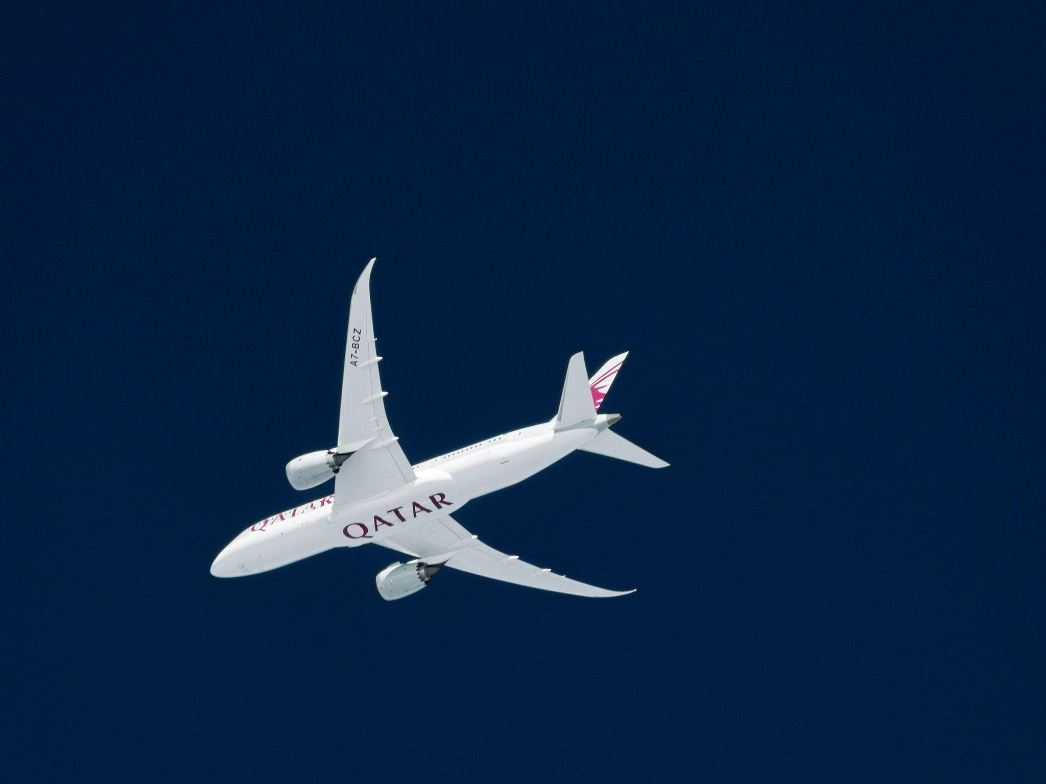 Qatar 桌布 壁紙 — 一架白色的卡塔爾航空飛機在沒有雲朵的深藍色天空中優雅翱翔。